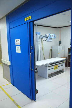 이 사진은 방사선실 사진입니다. 파란색 문으로 되어있고 제한구역표지판이 부착되어 있습니다. 