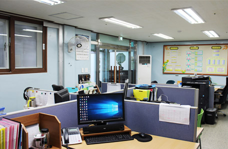 하늘색 벽으로 된 동명원 사무실 내부 전경으로 연보라색 파티션으로 구역이 나뉘어져 있는 모습