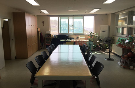 주간보호센터 사무실 내부에 테이블2개가 나란히 배치되어 있는 모습