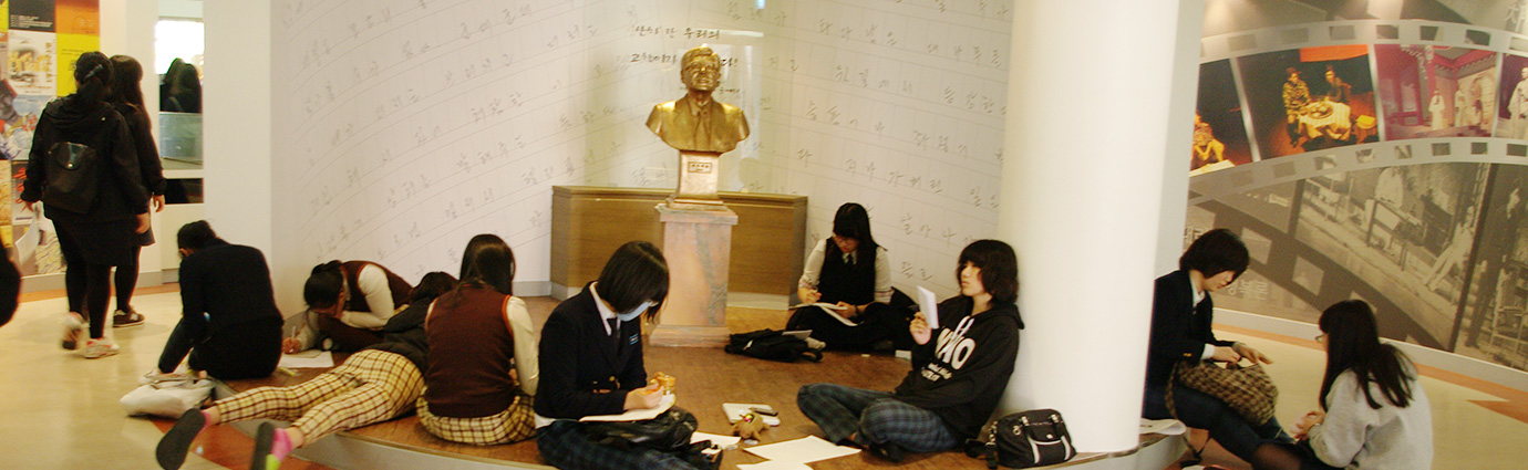 전시관 내부에 학생들이 둘러앉아 엽서나 편지를 쓰고있는 모습