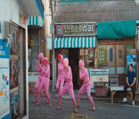 분홍색 쫄쫄이 복을 입은 5명의 사람이 연희네 슈퍼 앞에서 춤을 추고 있는 모습