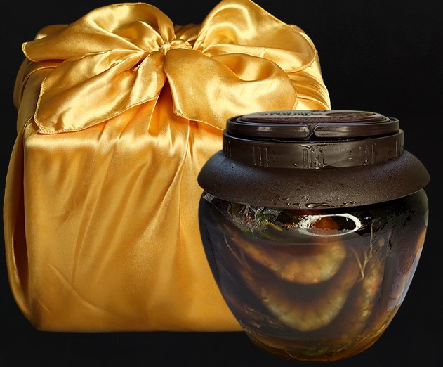 황금색 도자기로 포장된 박스와 갈색 뚜껑이 있는 통에 간장 새우가 함께 있는 사진