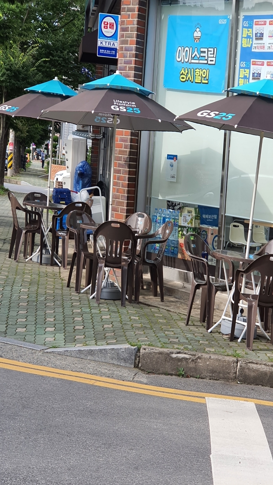 GS편의점 앞 3개의 파라솔과 3개의 테이블, 12개의 플라스틱의자가 보도블럭위에 펼쳐져있다
