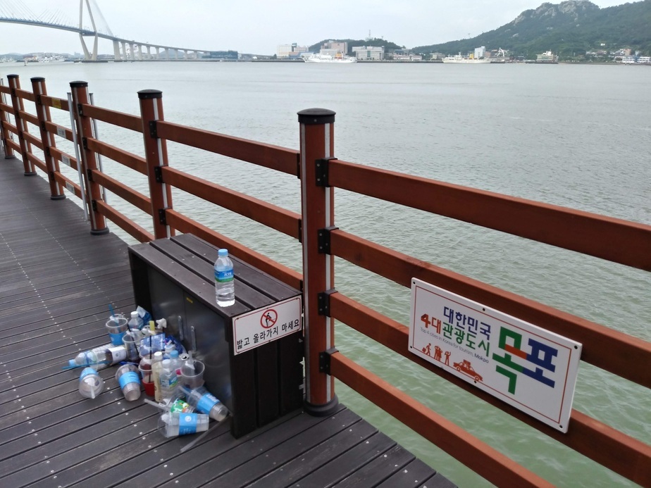 벤치에 밟고 올라가지마세요 앞 테이크아웃 플라스틱 음료잔과 500리터 플라스틱 쓰레기들이 쌓여있음
대한민국 4대관광도시 목포라고 데크울타리에 표지판이 붙어잇음