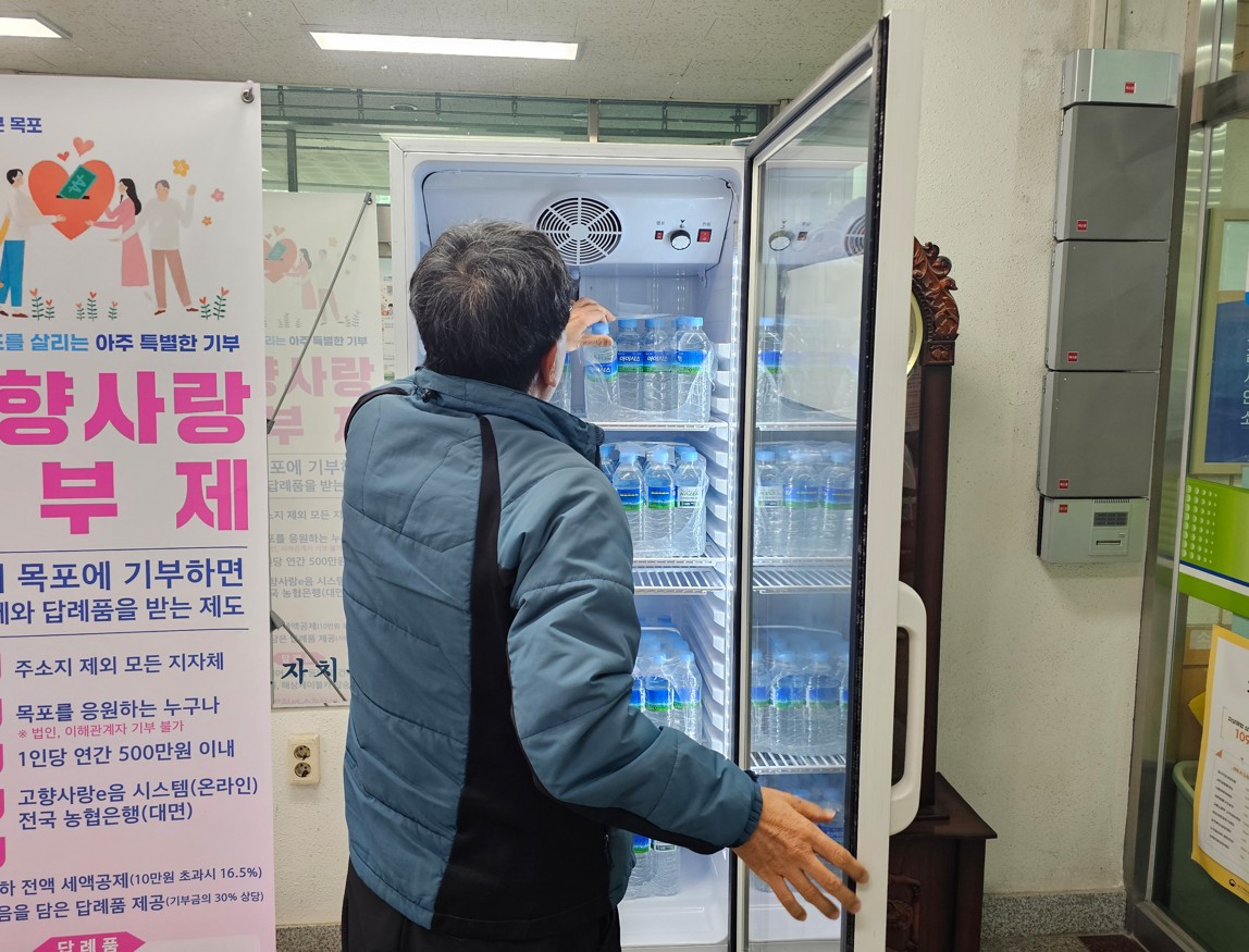 음료냉장고에 물을 채워넣고 있는 남성의 뒷모습