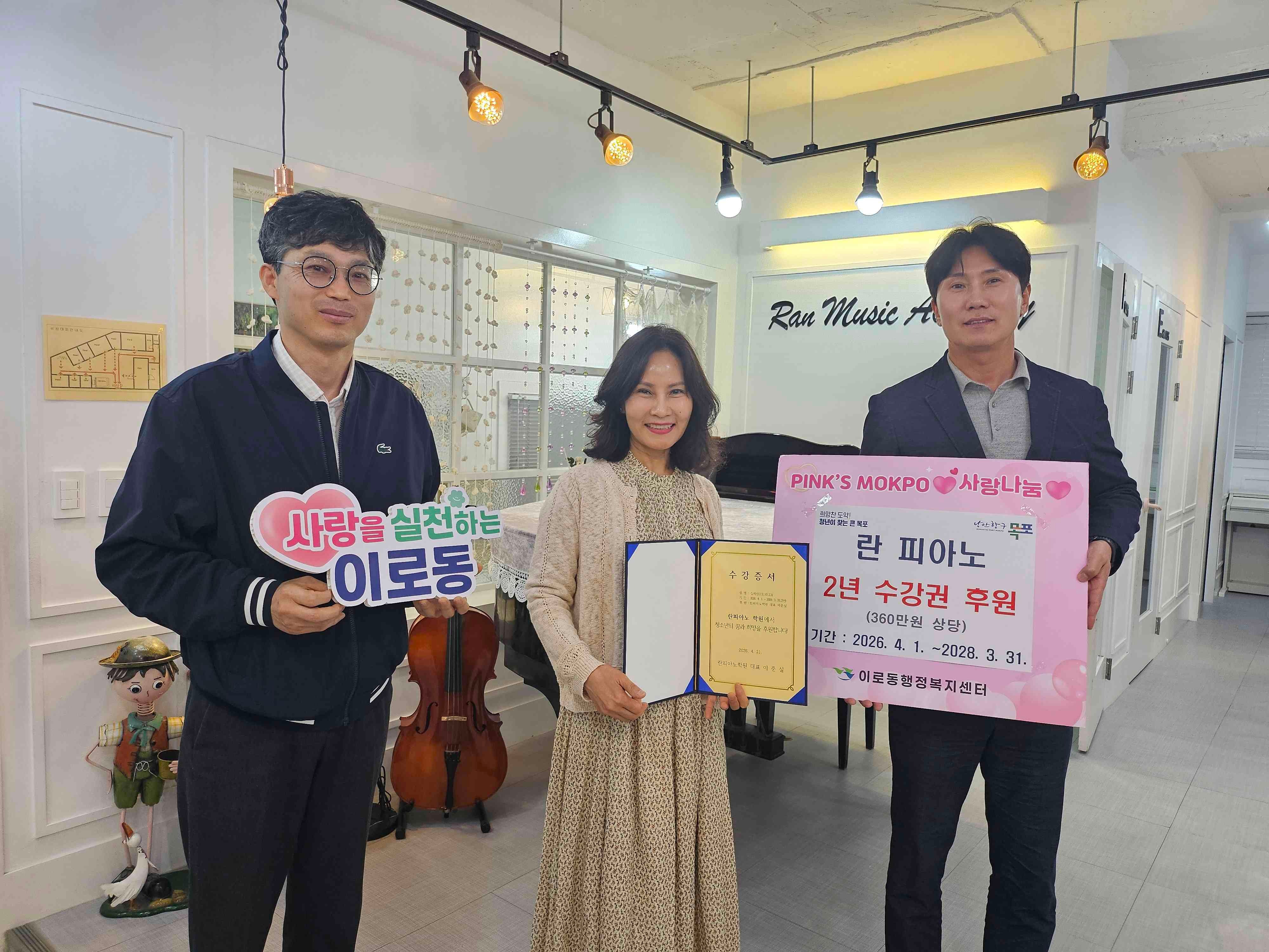 동 관계자들과 란피아노 관계자들이 팻말(사랑을 실천하는 이로동 란피아노학원, 이로동 청소년 위해 2년 무료 수강권(360만원 상당) 후원 기간:2026.4.1~2028.3.31 )을 들고 기념 촬영을 하는 모습