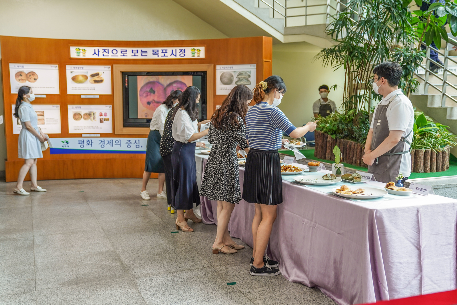 (07.31.상황실) 목포간편음식 개발 및 상품화 연구용역 중간시식 보고회 - 테이블에 놓이 으식들을 접시에 담고있는 참석자들 뒷모습.