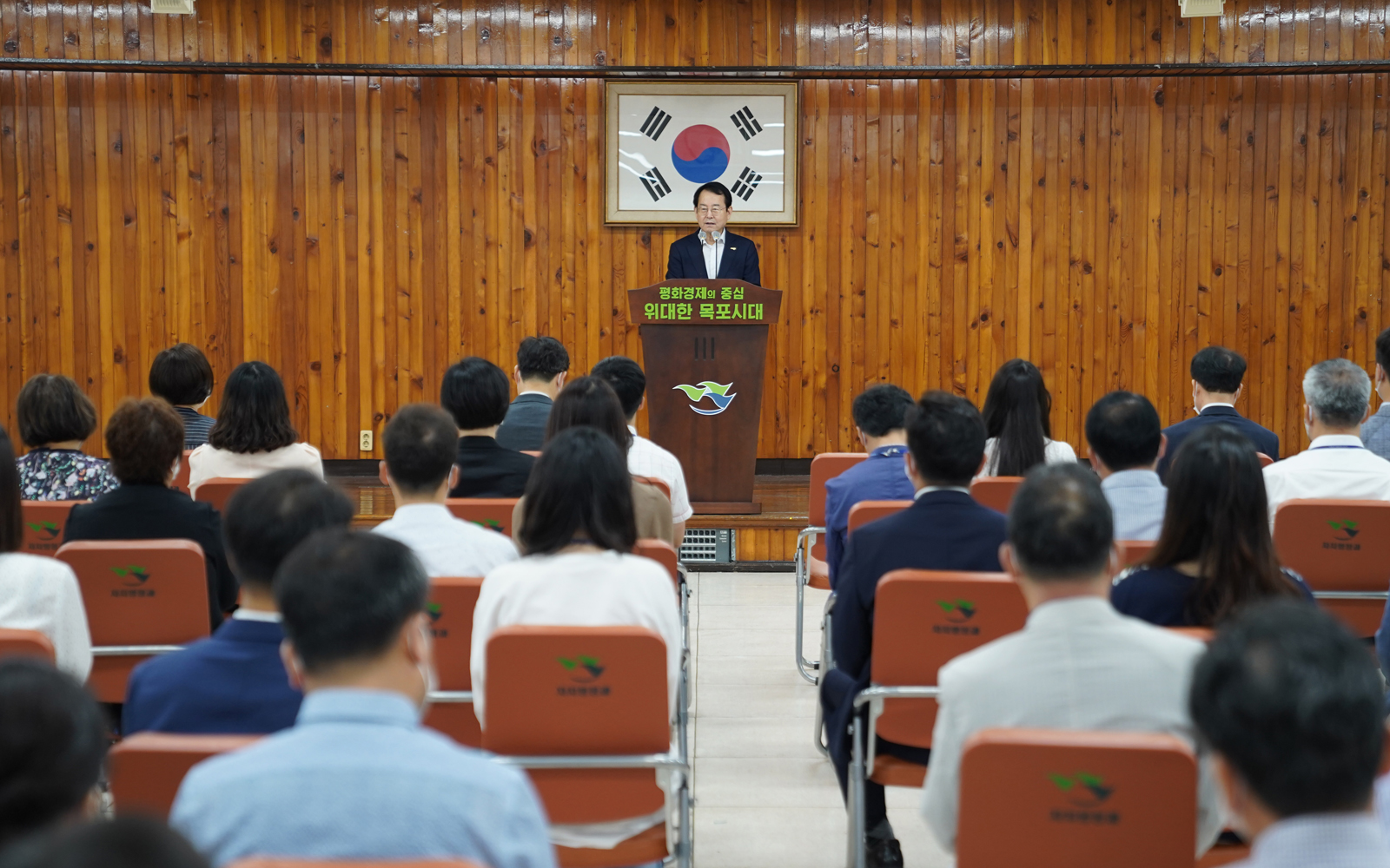(08.03.회의실) 8월 정례조회 - 단상에서 이야기중이 시장님과 의자에 앉아서 경청중인 참석자들 뒷모습. 