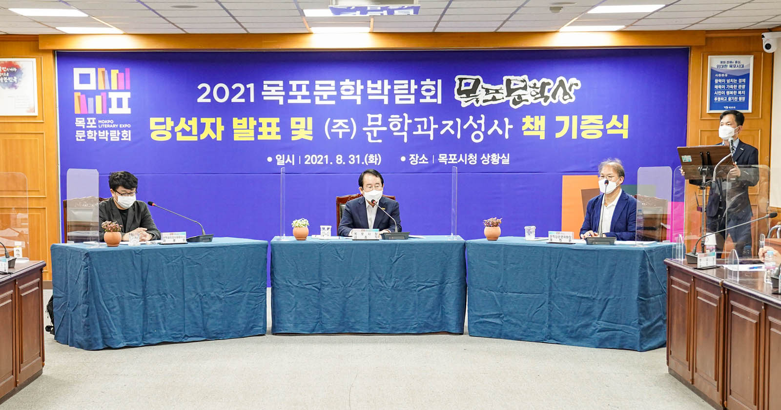 목포시청 상황실 정면에 세 개의 탁자가 놓여 있고 시장님 비롯 세 명이 나란히 않아 기증식을 하고 있는 모습이다