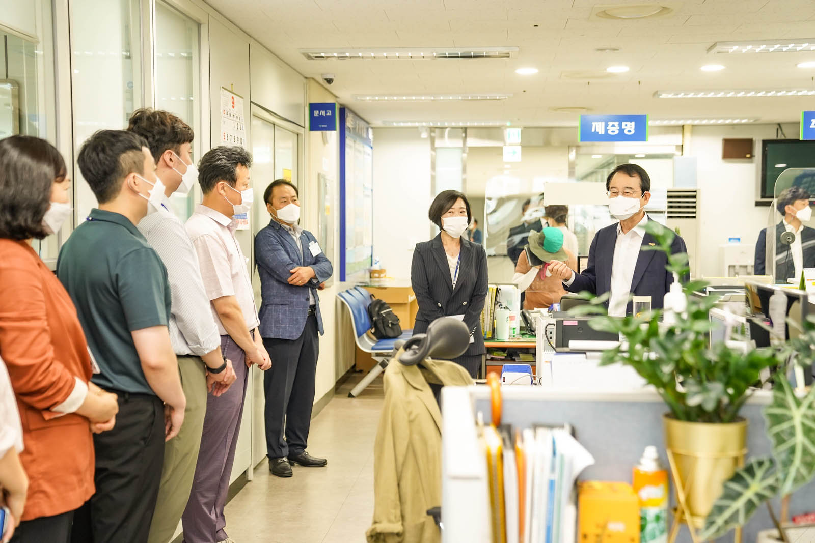 주민센터 관계자들이 일렬로 서 있고 시장님이 이야기 하고 있는 사진이다.
