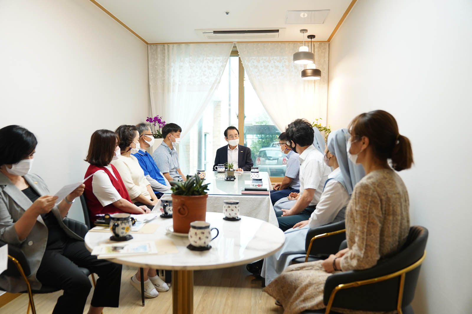 시장님과 수녀님 등 관계자들이 차를 놓고 담화하고 있다