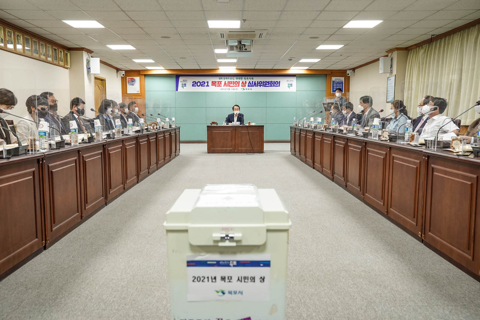 목포시민의 상 심사위원회에 회의 중인 모습이다. 시장님이 가운데 양 가로 참석자들이 앉아 있고 가운데 2021년 목포 시민의 상이라고 적힌 투표함이 보인다.