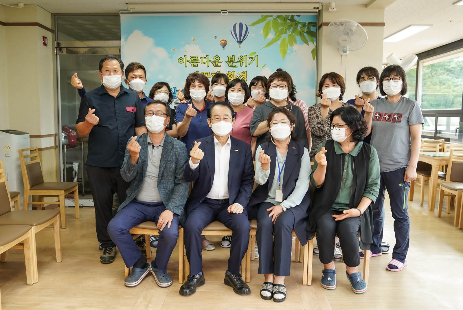 시장님과 복지시설 관계자들이 손가락 하트를 하고 기념촬영을 하고 있다 
