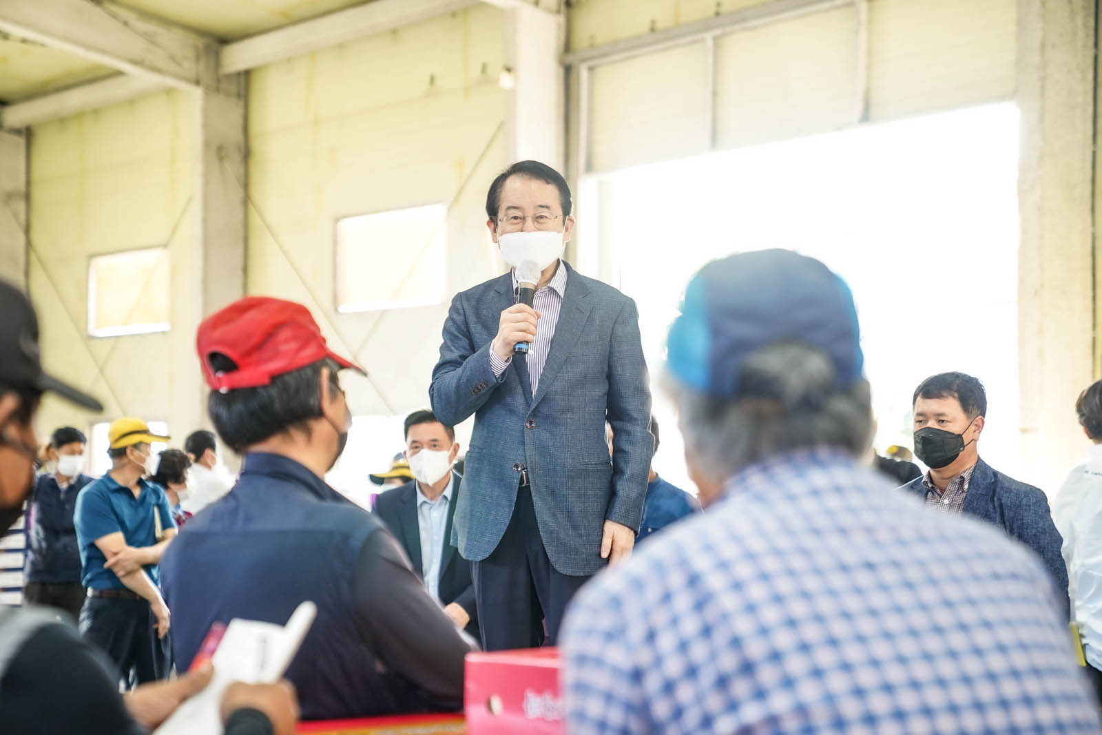시장님이 전통시장을 방문해 상인들 앞에서 말씀 중인 사진이다