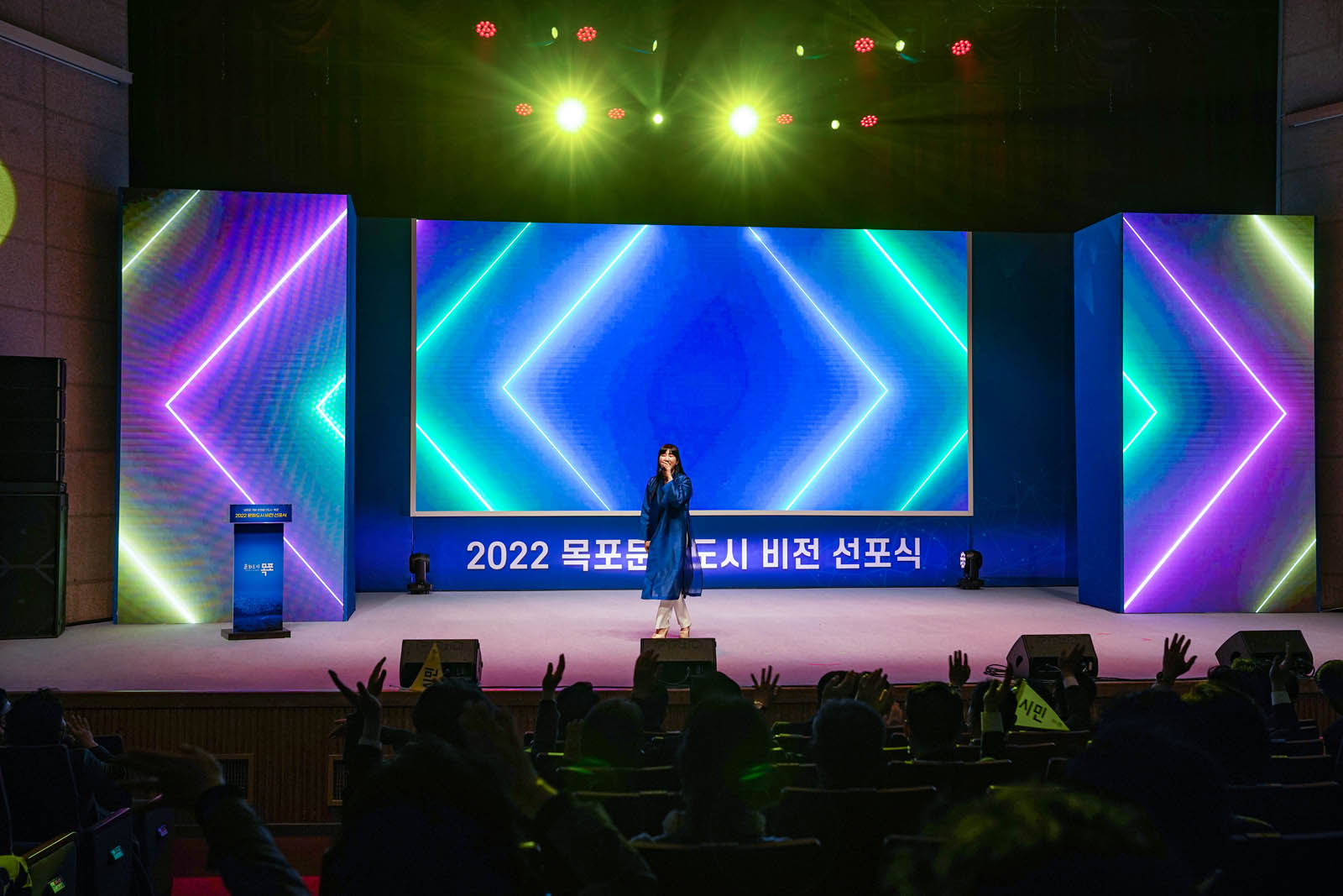 (03.23.문화예술회관) 문화도시 비전 선포식에서 파란 드레스를 입은 여성이 무대에 서 있다.