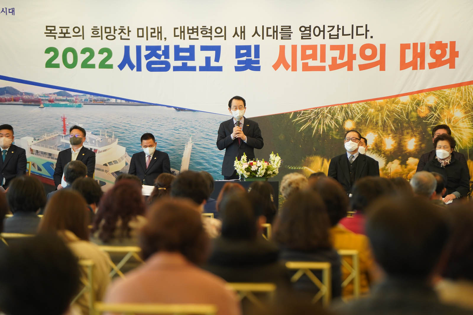 (03.28.예술웨딩컨벤션) 시정보고를 진행하는 목포시장 모습으로 뒤로 목포의 희망찬 미래, 대변혁의 새 시대를 열어갑니다. 2022 시정보고 및 시민과의 대화라고 크게 적혀 있다.