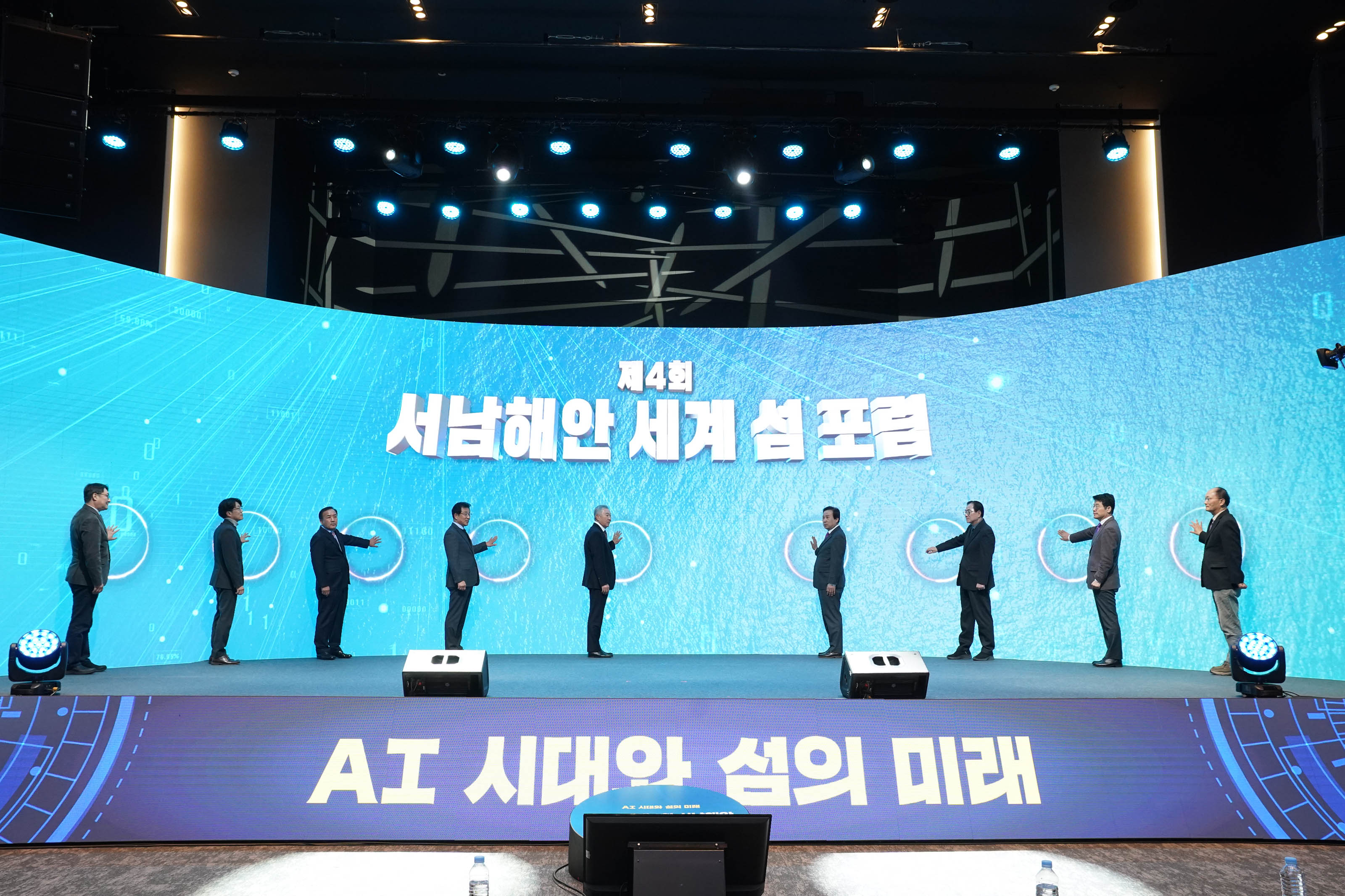 제 4회 서남해안 세계 섬포럼 AI 시대와 섬의 미래라고 적힌 단상위에서있는 9명의 관계자들