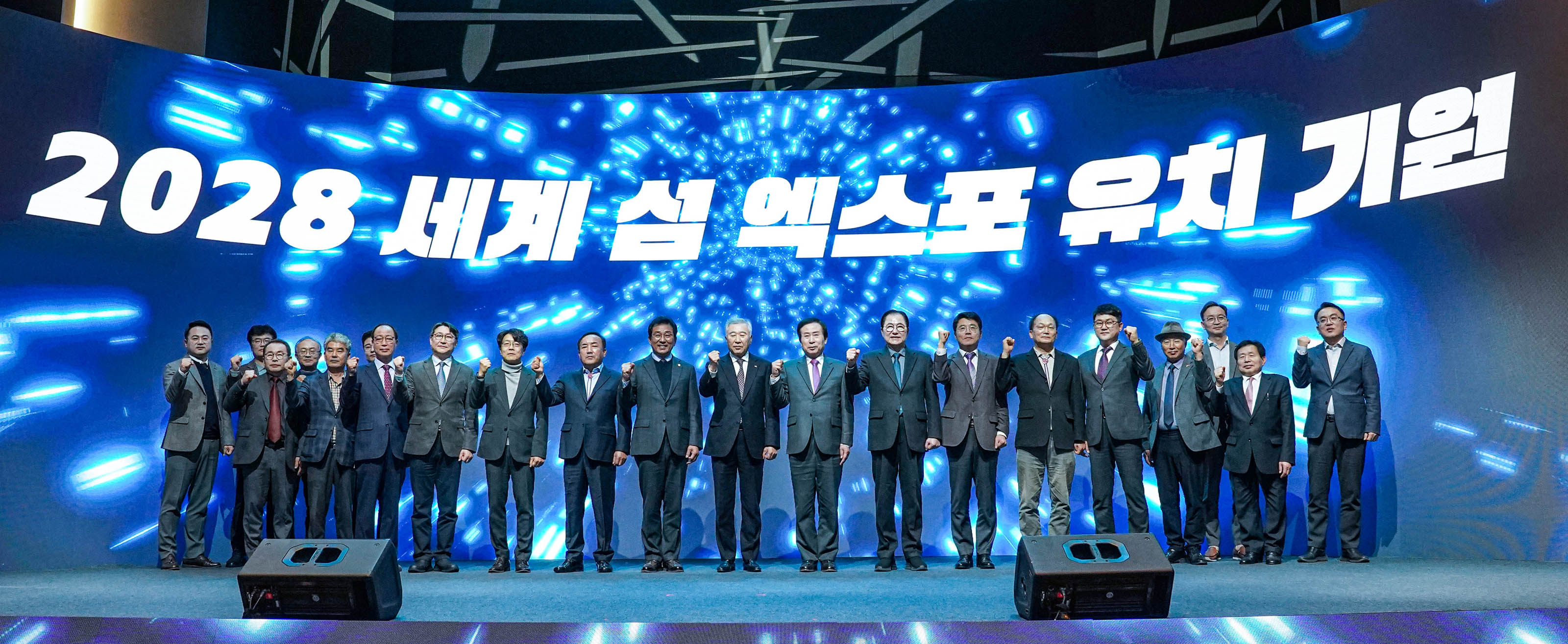 2028 세계 섬 엑스포 유치기원 배경을두고 단상위에서 화이티 포즈를 취하는 관계자 단체사진
