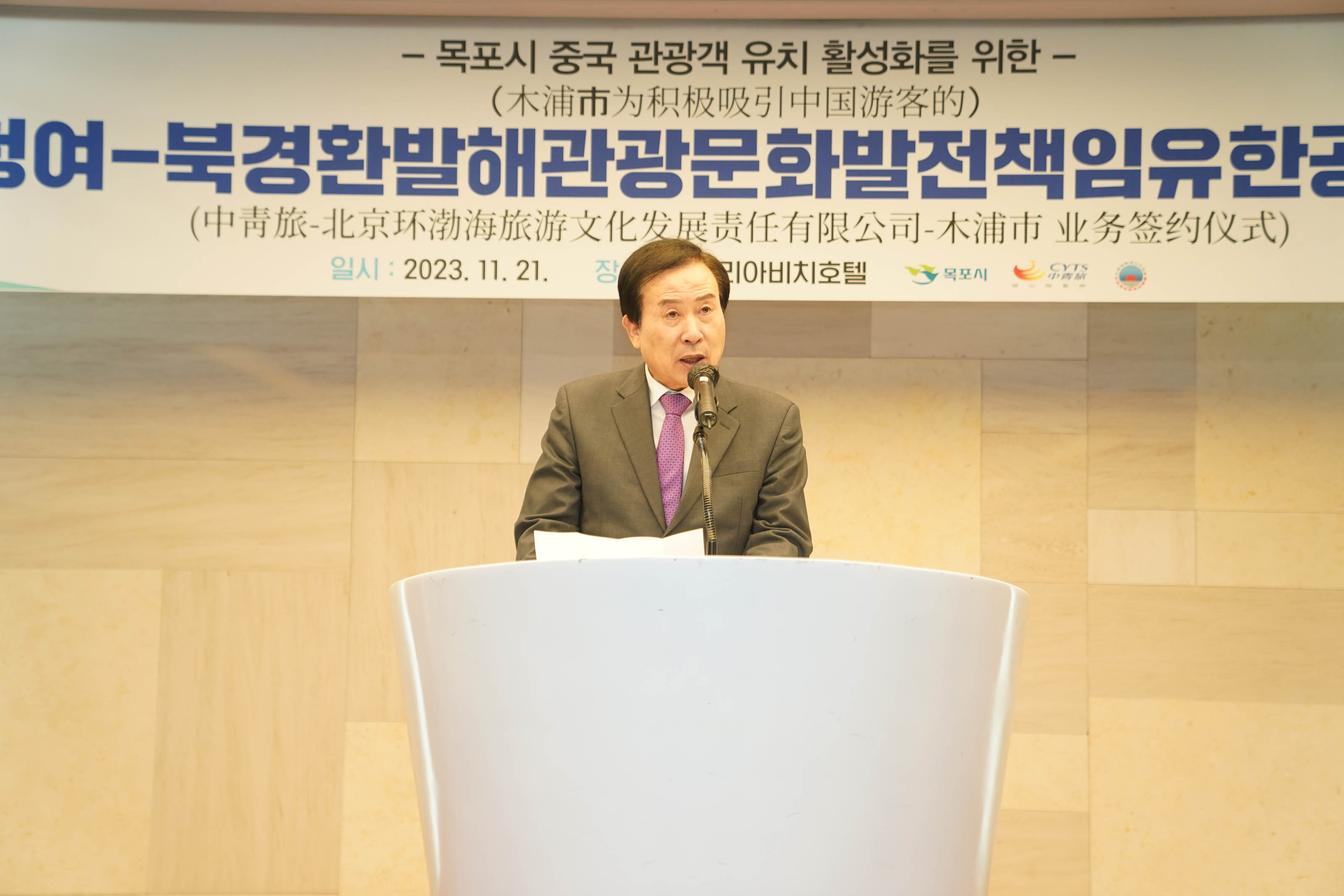 목포시 중국 관광객 유치 활성화를 위한 목포시 중청여 북경환발해관광문화발전책임유한공사 업무 협약식 플랜카드를 뒤에두고 단상위에서 박홍률 목포시장이 연설하는 모습이 담긴 독백사진