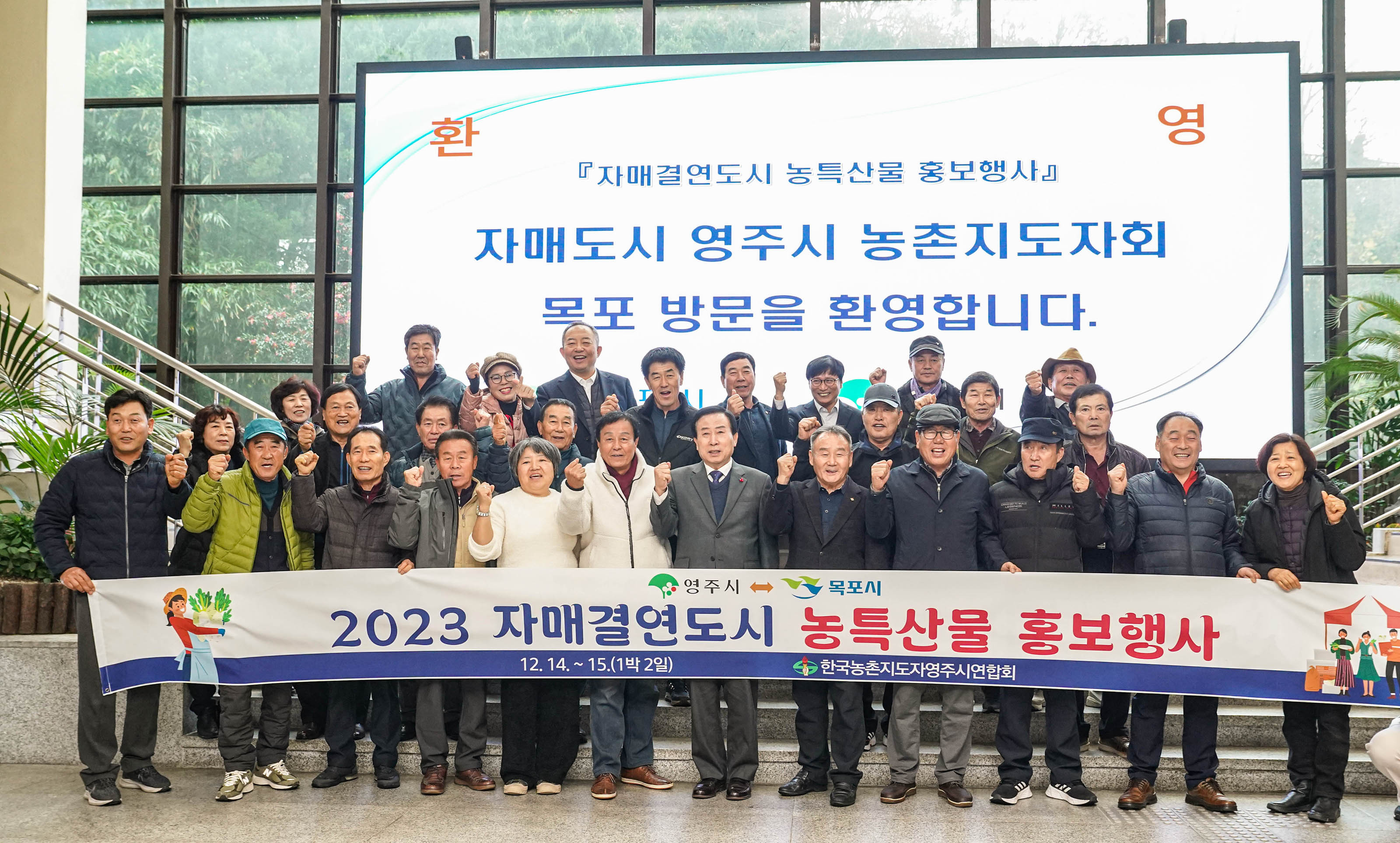 환영 자매결연도시 농특산물 홍보행사 자매도시 영주시 농촌지도자회 목포 방문을 환영합니다 배경을두고 영주시 목포시 2023 자매결연도시 농특산물 홍보행사 플랜카드를 들고 화이팅포즈를 취하며 단체 사진찍는 관계자들
