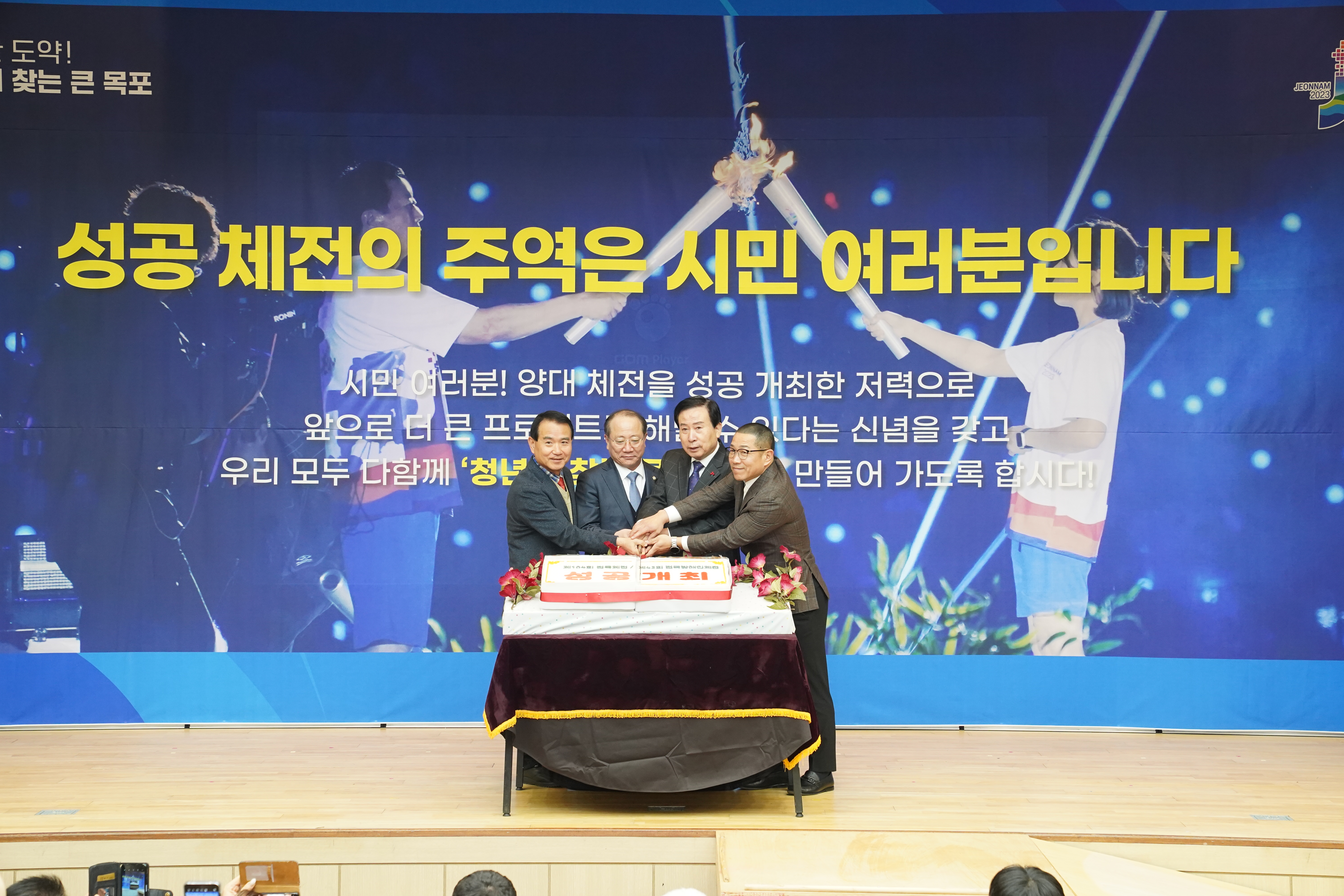 성공 체전의 주역은 시민여러분입니다. 글이 적힌 배경을두고 컷팅식을하는 관계자와 목포시장 박홍률