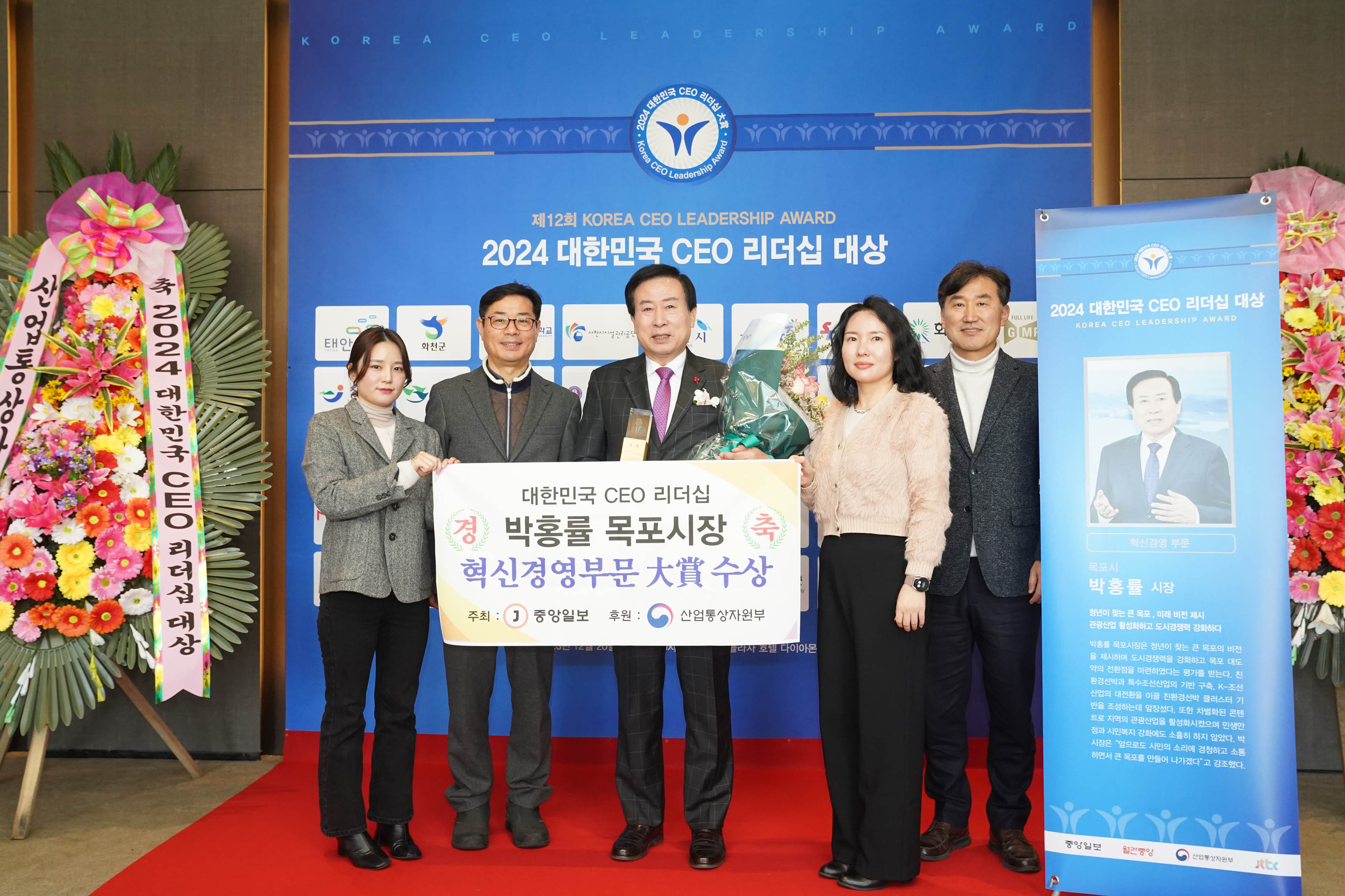제 12회 KOREA CEO LEADERSHIP AWARD 2024 대한민국 CEO 리더쉽 대상 배경을두고 대한민국 CEO 리더쉽 경축 박홍률 목포시장 혁신경영부분 대상 수상 플랜카드를 들고있는 목포시장 박홍률과 관계자들