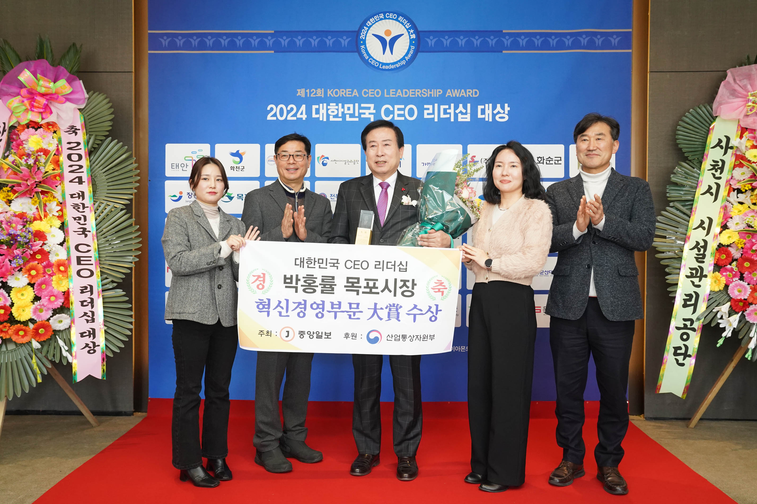 제 12회 KOREA CEO LEADERSHIP AWARD 2024 대한민국 CEO 리더쉽 대상 배경을두고 대한민국 CEO 리더쉽 경축 박홍률 목포시장 혁신경영부분 대상 수상 플랜카드를 들고있는 목포시장 박홍률과 관계자들2