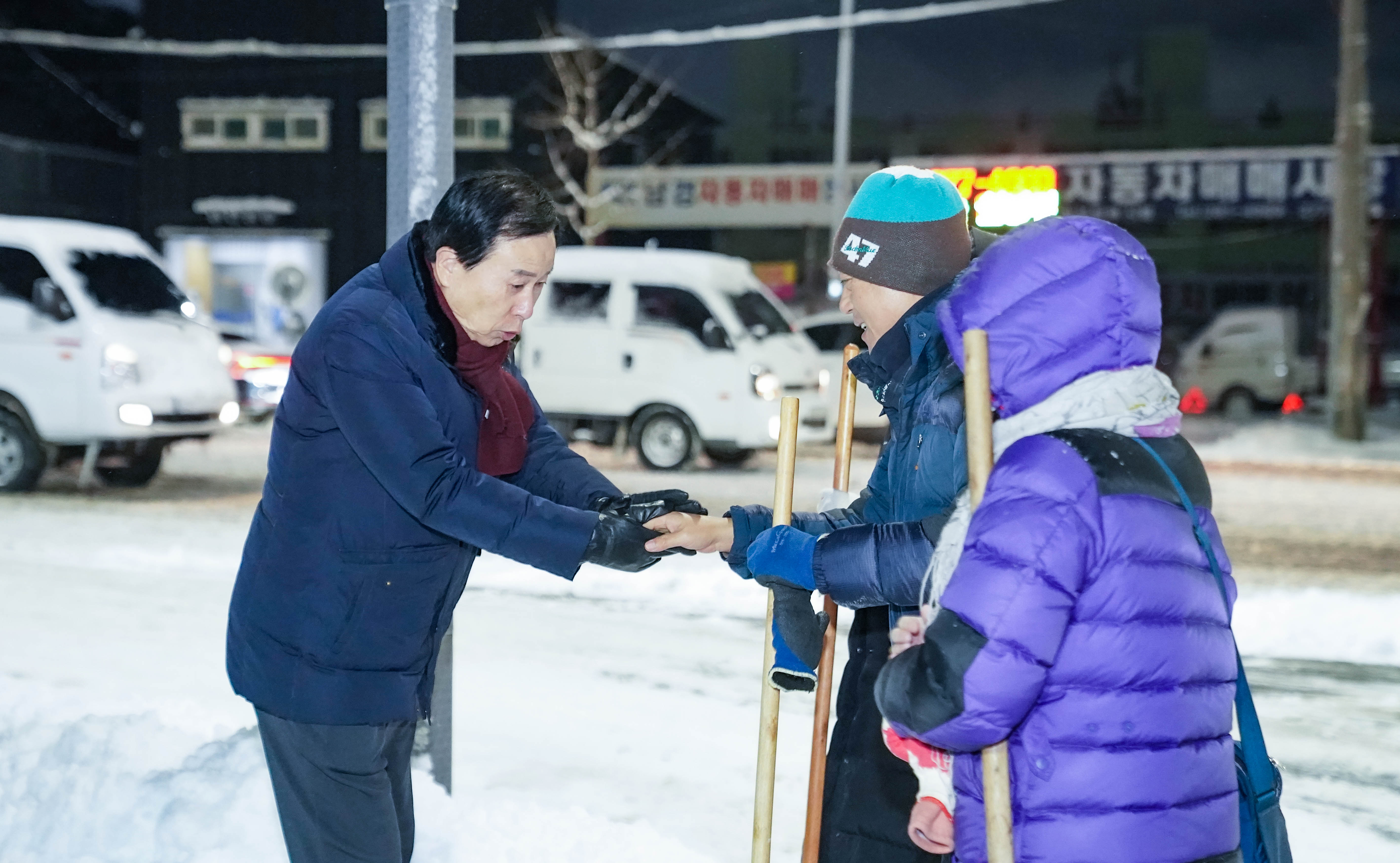 손을 잡으며 대화중인 목포시장 박홍률과 제설작업중인 시민