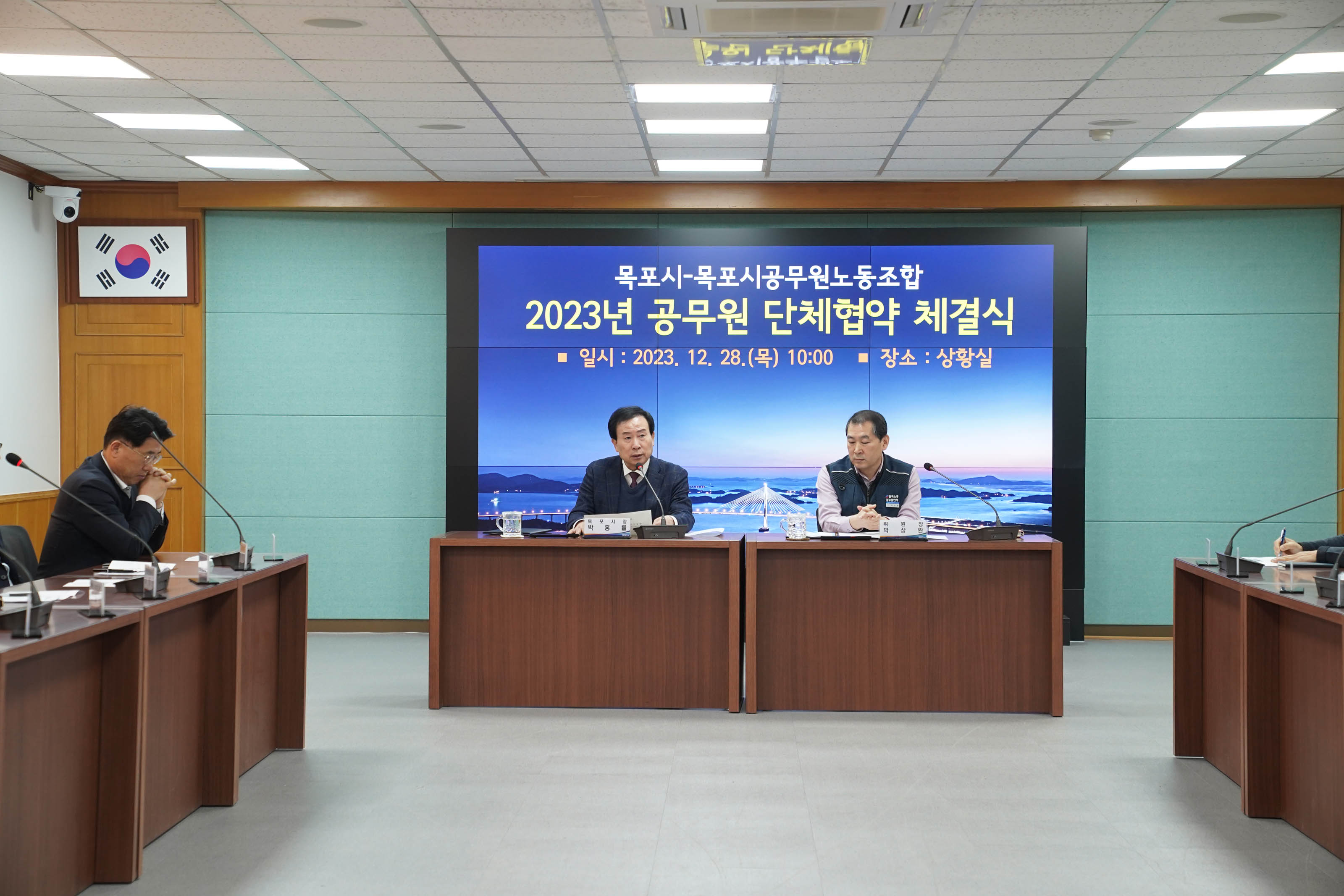 목포시 목포시공무원노동조합 2023 공무원 단체협약 체결식 일시 : 2023.12.28(목) 10:00 장소:상황실이 적혀있는 배경 앞에서 연설중인 목포시장 박홍률과 경청하는 관계자들