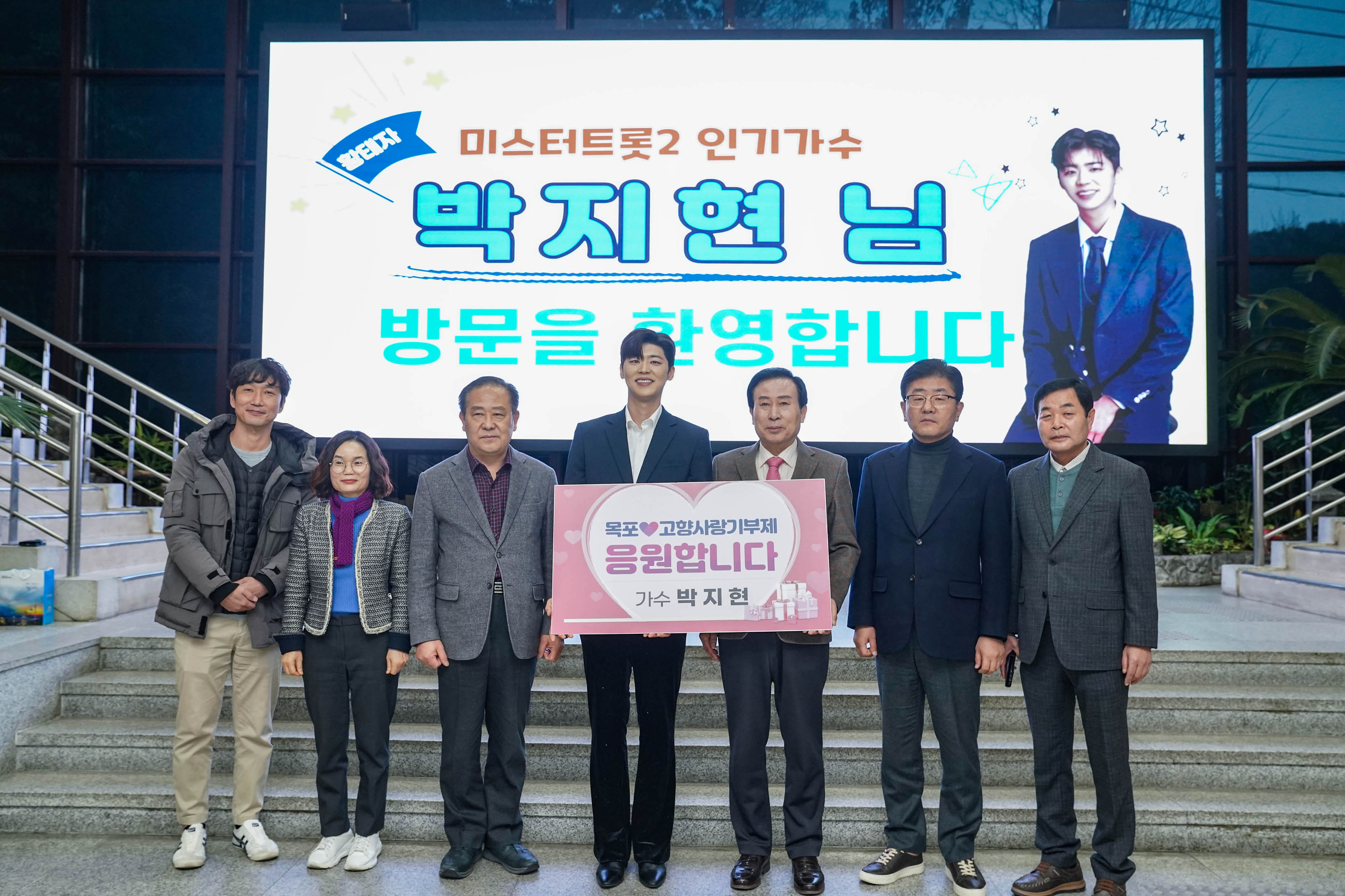 목포 고향사랑기부제 응원합니다 가수 박지현 플랜카드를 들고있는 가수 박지현과 목포시장 박홍률 그리고 관계자들 단체사진