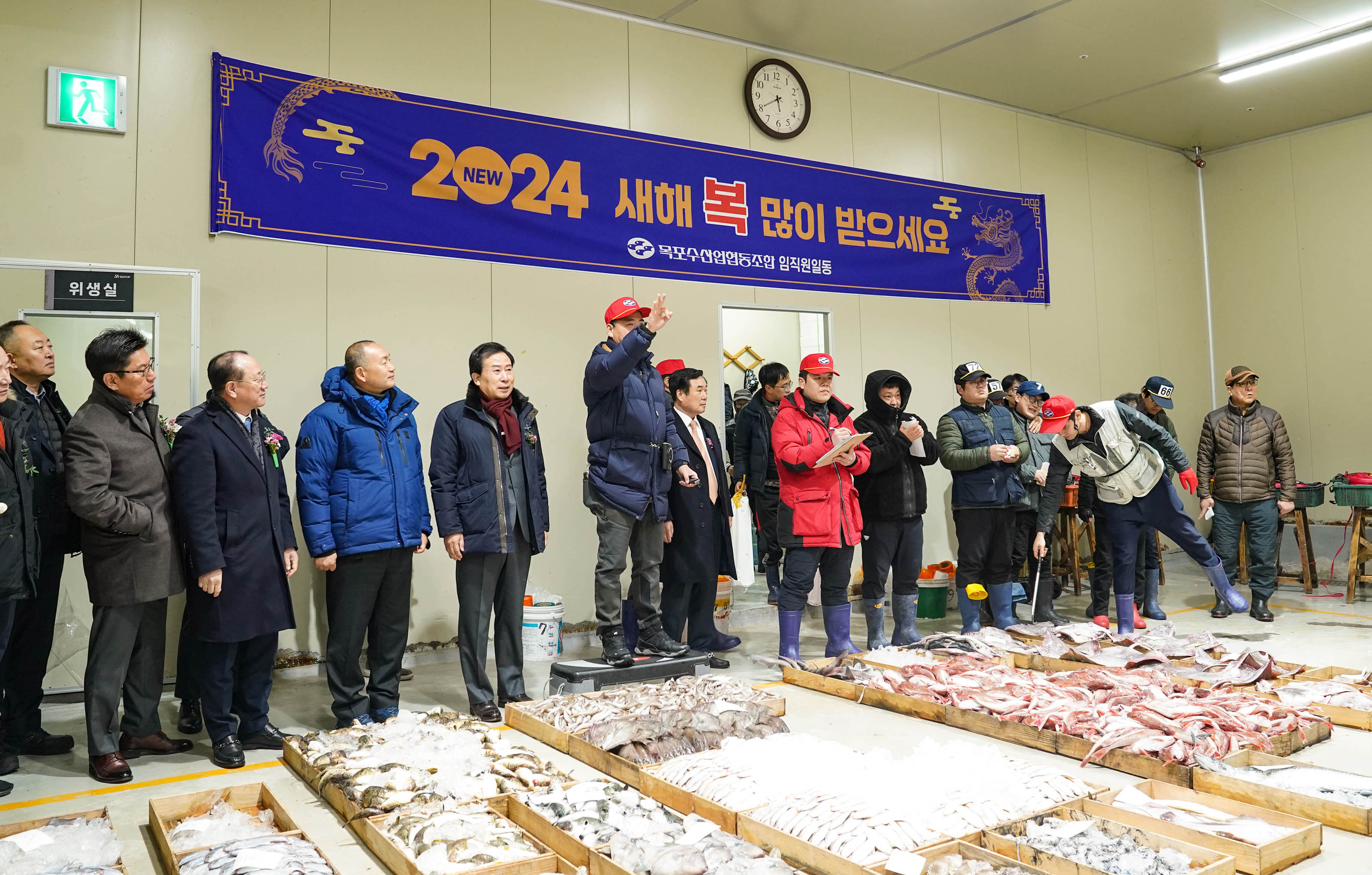 2024 새해복 많이 받으세요 목포수산형동조합 임직원일동 현수막 앞에서 수산물 경매중인 어민들과 시장 박홍률 외 관계자들