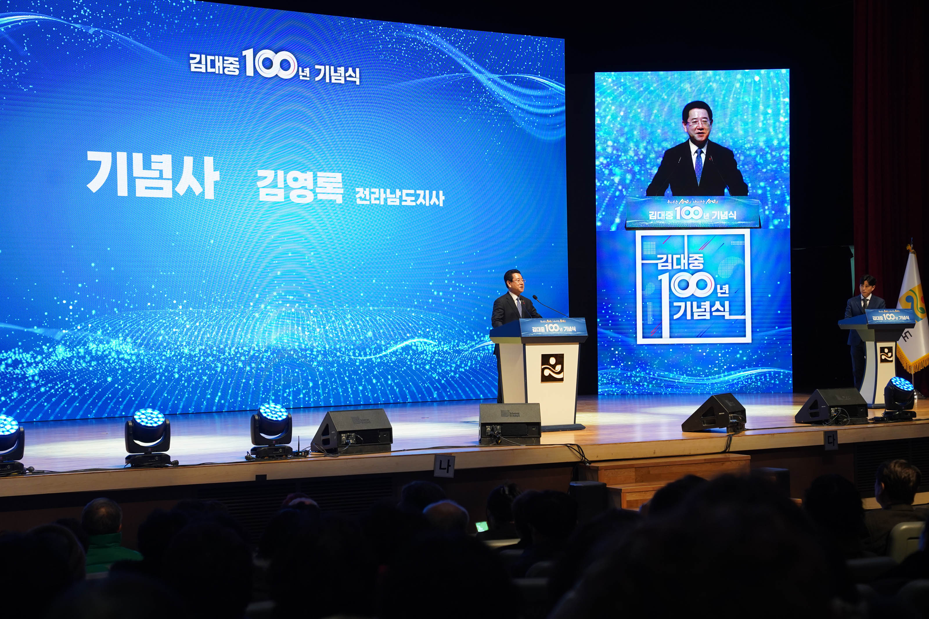 김대중 100년 기념식 기념사 김영록 전라남도지사 화면과 김대중100년 기념식 화면을 배경으로두고 연단위에서 연설하는 김영록 전라남도지