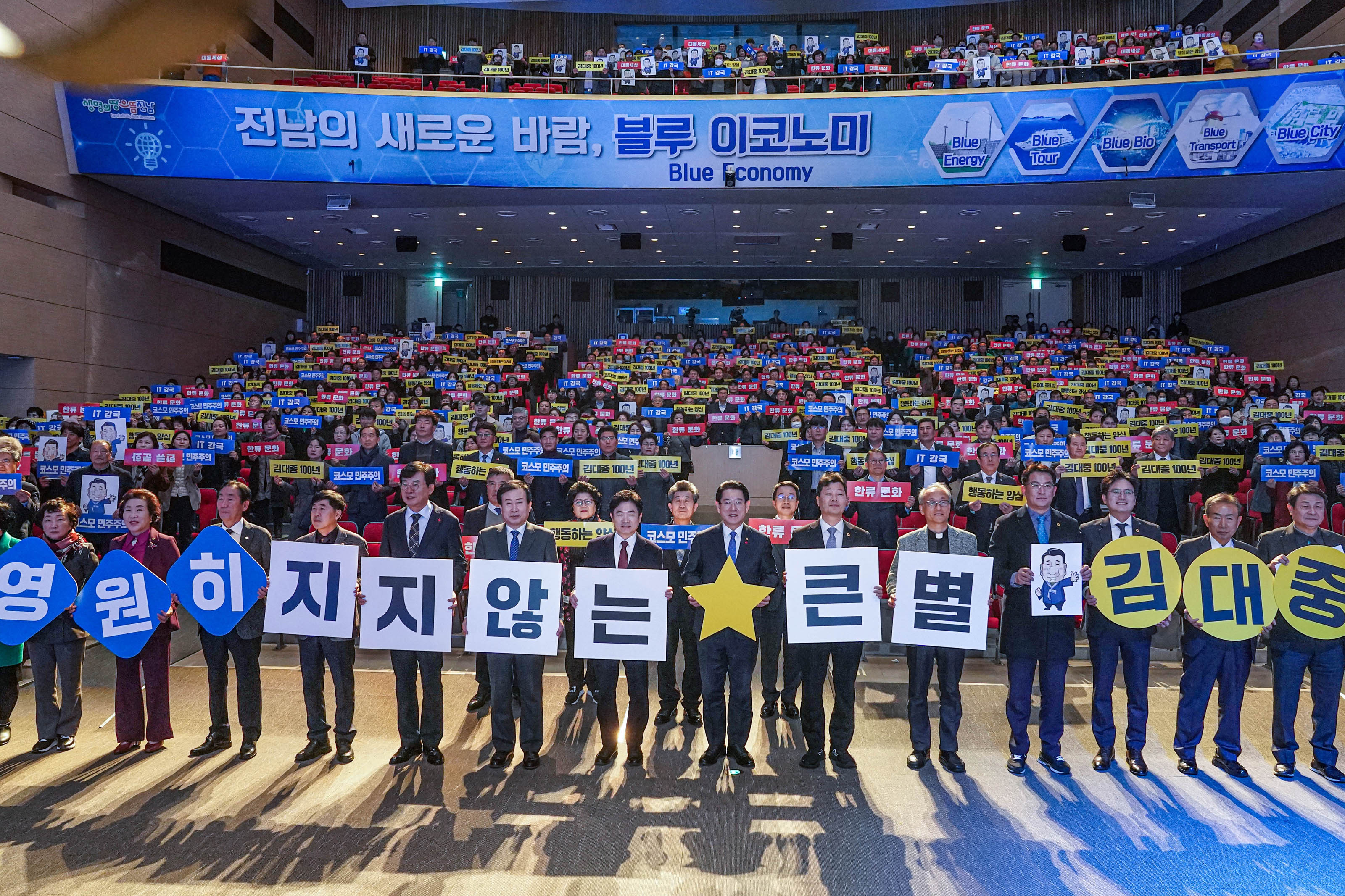 전남의 새로운 바람, 블루 이코노미 현수막을 위에두고 영원히 지지않는 큰별 김대중 글을 들고 청중과 함께 사진찍는 관계자들