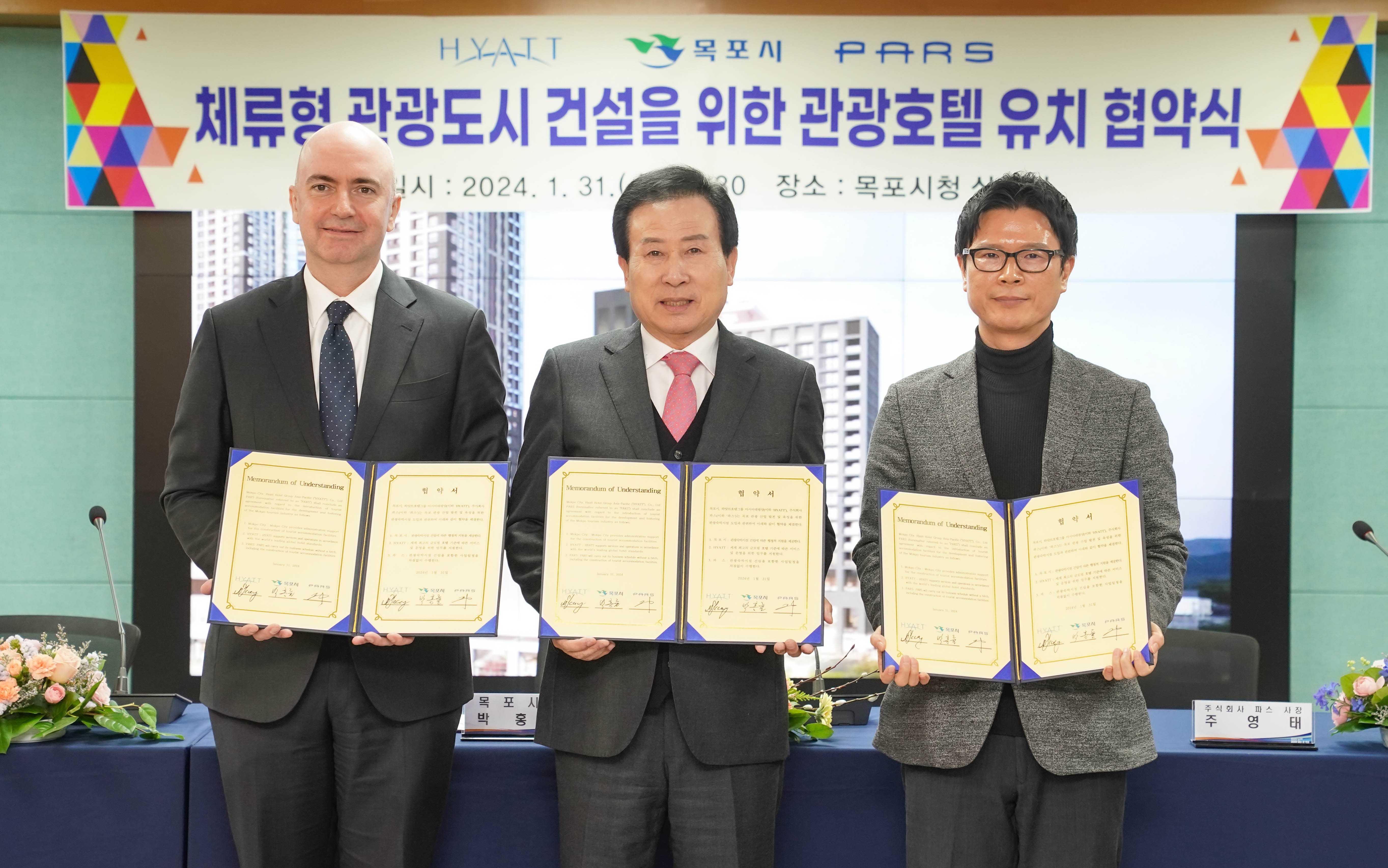 HYATT 목포시 PARS체류형 관광도시 건설을 위한 관광호텔 유치 협약식 일시 : 2024. 1. 31(수) 16:30 장소 : 목포상황실 현수막 아래에서 협약서를 들고 있는 박홍률 시장과 관계자들
