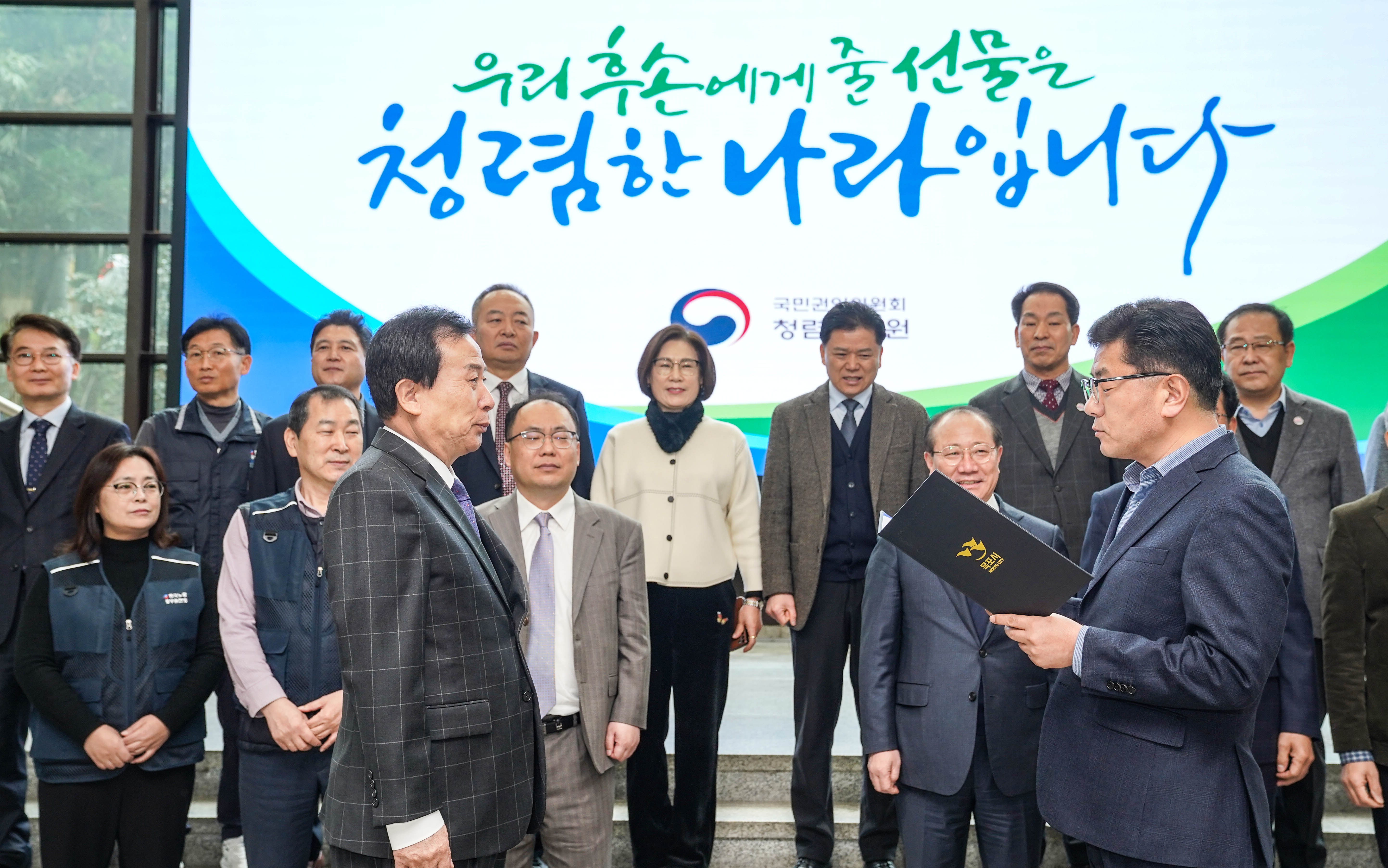 우리후손에게 줄 선물은 청렴한 나라입니다 글을 배경으로 수여식중인 박홍률시장과 관계자들