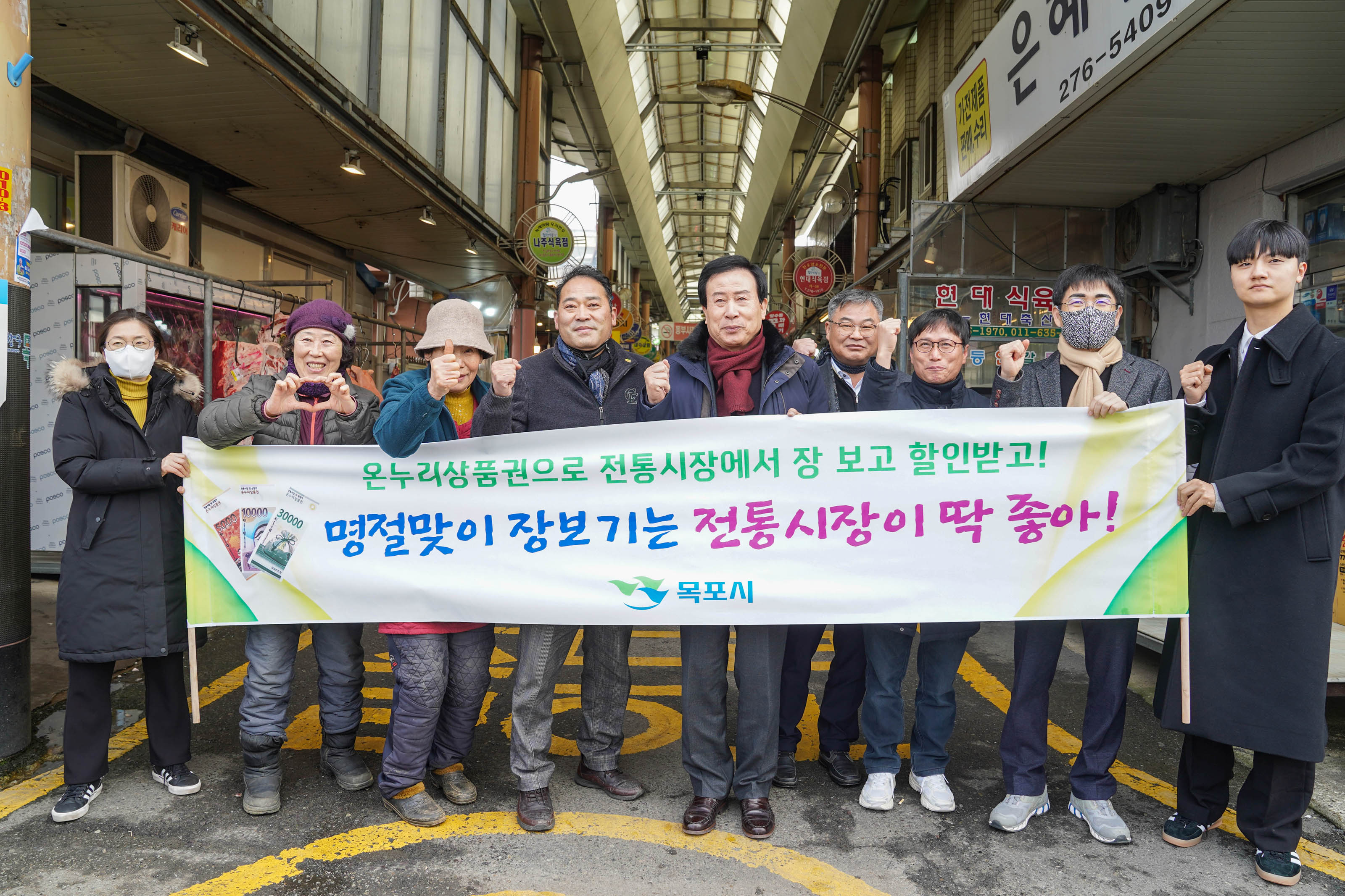 남진야시장 배경으로 온누리상품권으로 전통시장에서 장 보고 할인받고! 명절맞이 장보기는 전통시장이 딱 좋아! 목포시장 플랜카드를 들고 화이팅 포즈를 취하는 박홍률 시장과 관계자들2