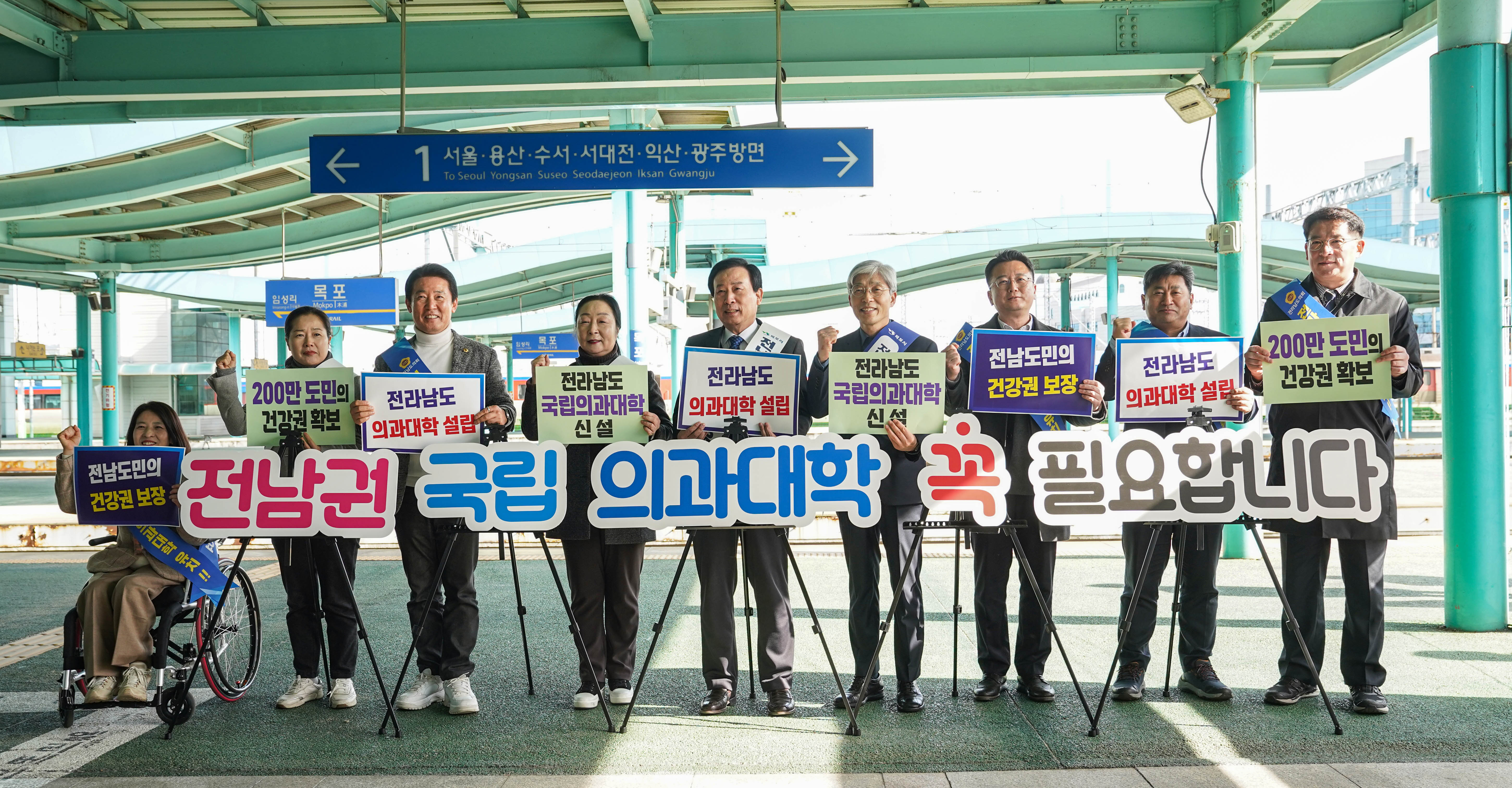 1서울 용산 수서 서대전 익산 광주방면 안내판 앞에서 전남권 국립 의과대학 꼭 필요합니다 문구를 앞에두고 각각 전남도민의 건강권 보장, 200만 도민의 건강권 확보, 전라남도 의과대학 설립, 전라남도 국립의과대학 신설 플랜카드를 들고 있는 박홍률시장과 관계자들