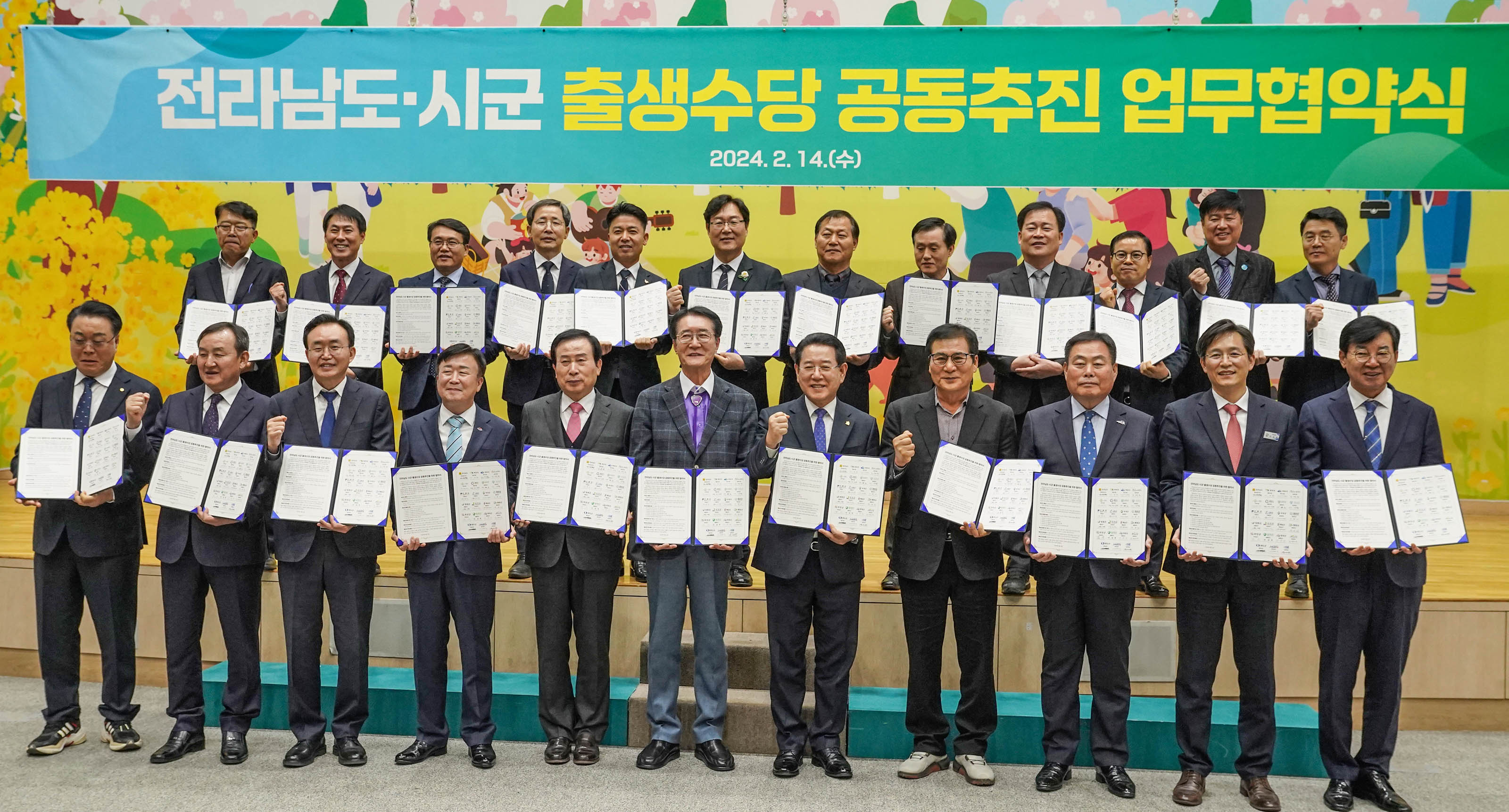 전라남도 시군 출생수당 공동추진 업무협약식 2024.2.14(수) 플랜카드밑에서 협약서를 들ㄹ고 화이팅 포즈를 취하는 관계자들
