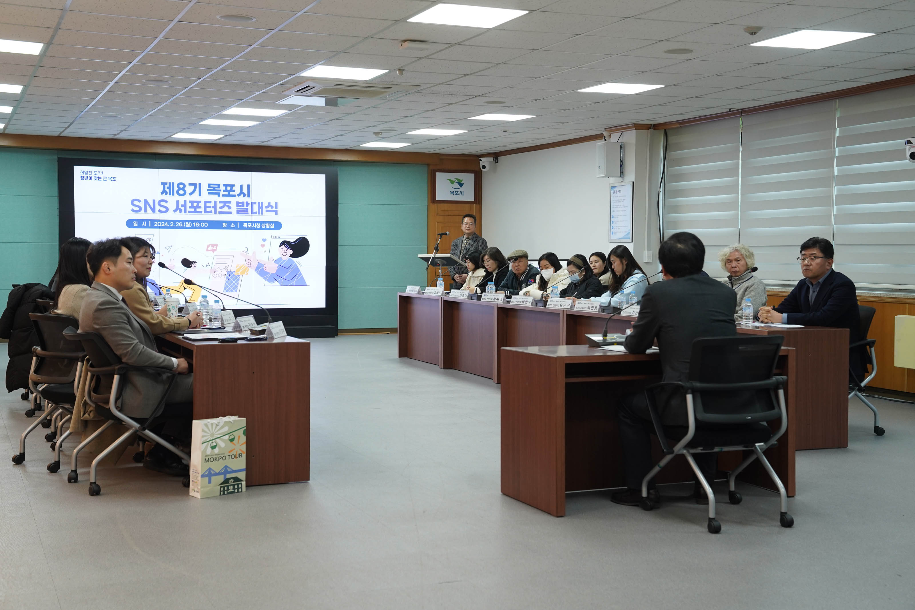 제8기 목포시 SNS 서포터즈 발대식이라는 화면이 띄워져있고, 마주보고 앉은 박홍률 시장의 뒷모습이 보인다. 희의 참석자들은 박홍률 시장을 바라보고 있다.