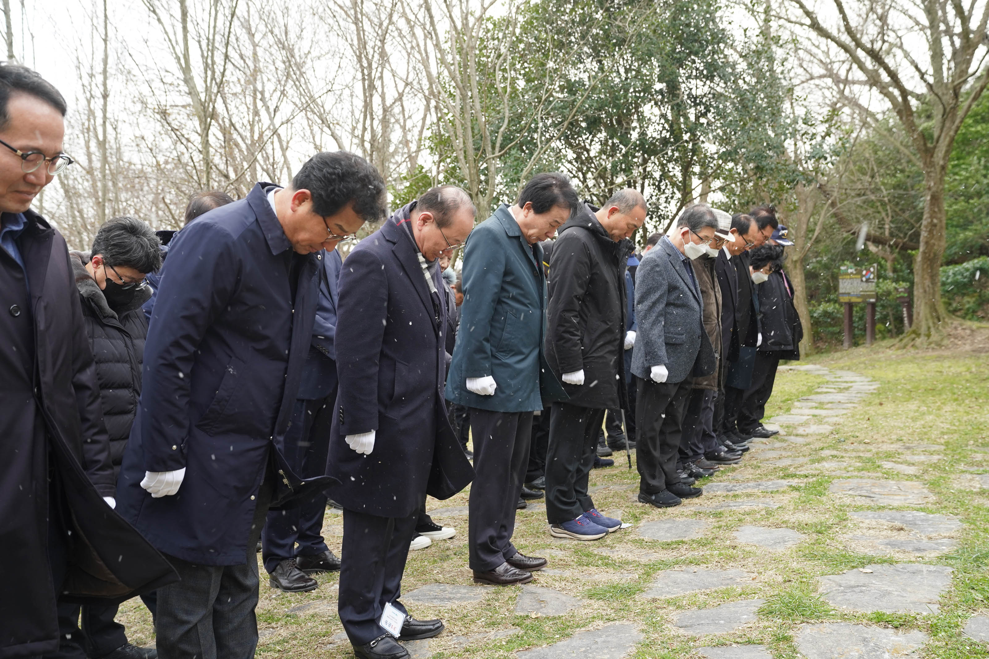 흰색 장갑을 착용한 주먹을 가볍게 쥐고 기념탑에 묵념하는 박홍률 시장과 그의 옆에 나란히 선 맨 앞줄 사람들의 모습에 포커스가 맞춰진 사진