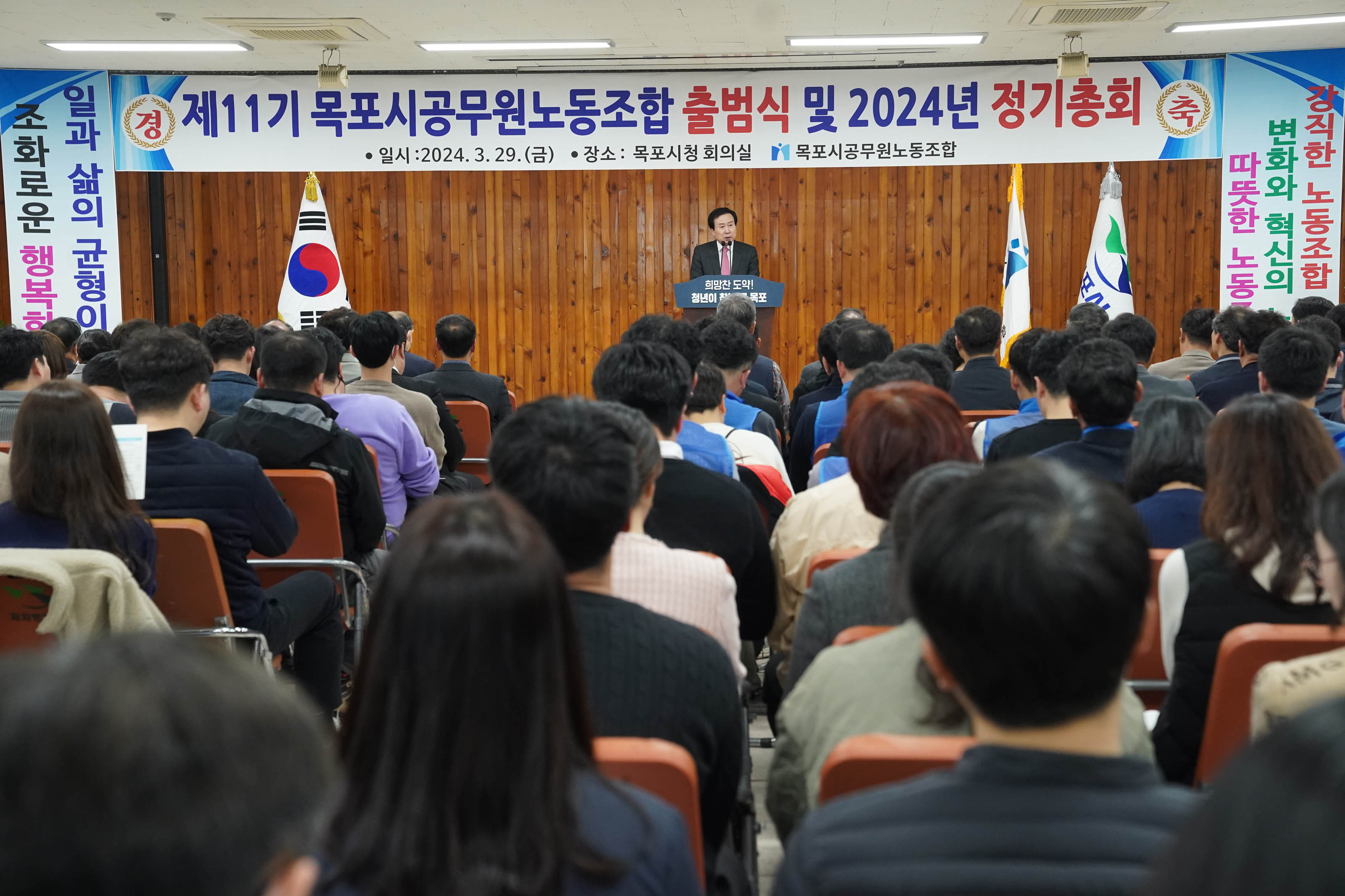 제 11기 목포시공무원노동조합 출범식 및 2024년 정기총회 일시:2024.3.29(금) 장소:목포시청 회의실 목포시공무원노동조합 현수막이 중심으로 걸려있고, 박홍률 시장이 단상에 서서 이야기 하고 있다. 그 앞으로 얘기를 경청하고 있는 사람들이 앉아있다.