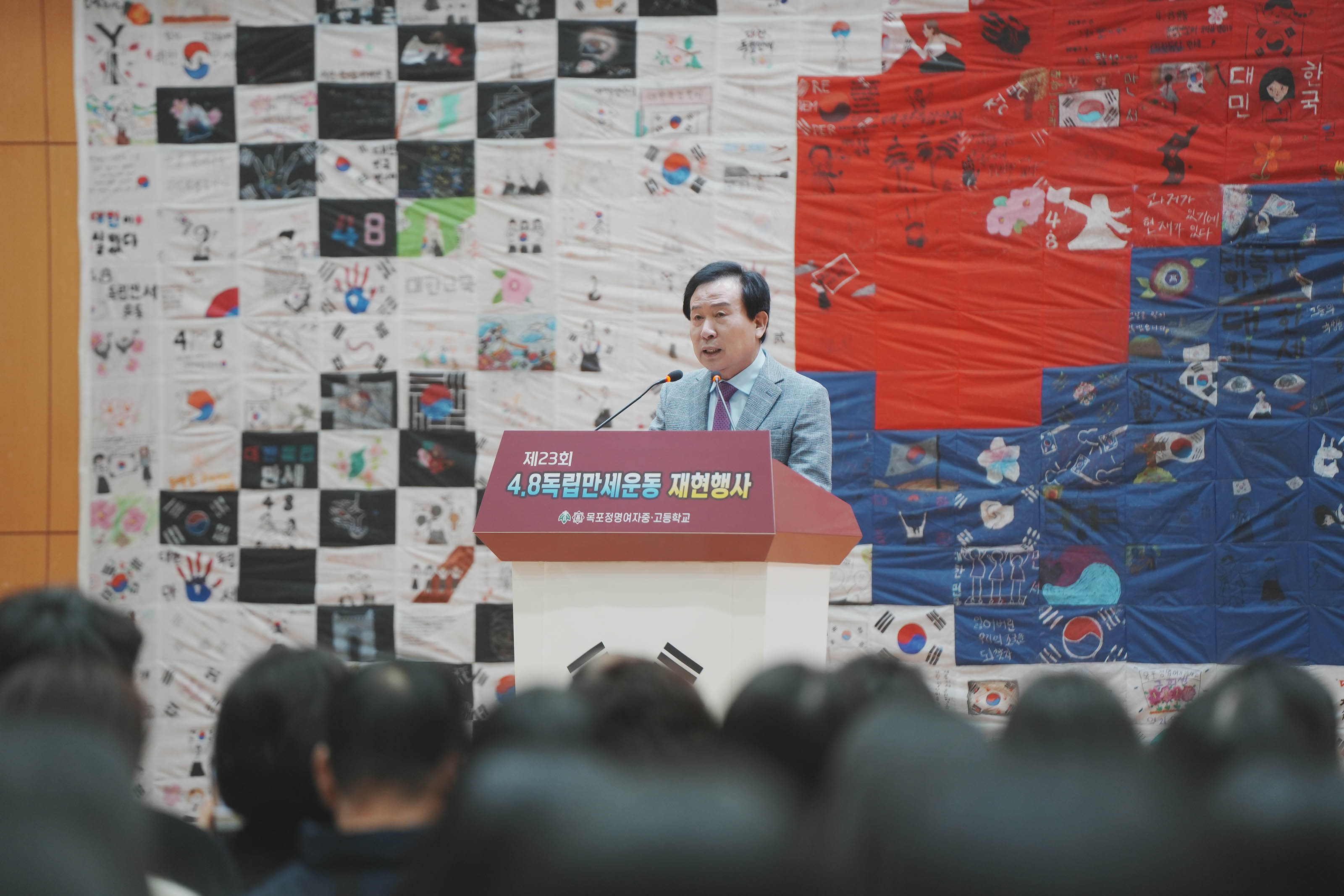 목포정명여자 중,고등학교에서 진행한 제23회 4.8독립만세운동 재현행사에서 박홍률 시장이 단상앞에서 얘기하고 있다. 뒤로 태극기 작품이 보인다.