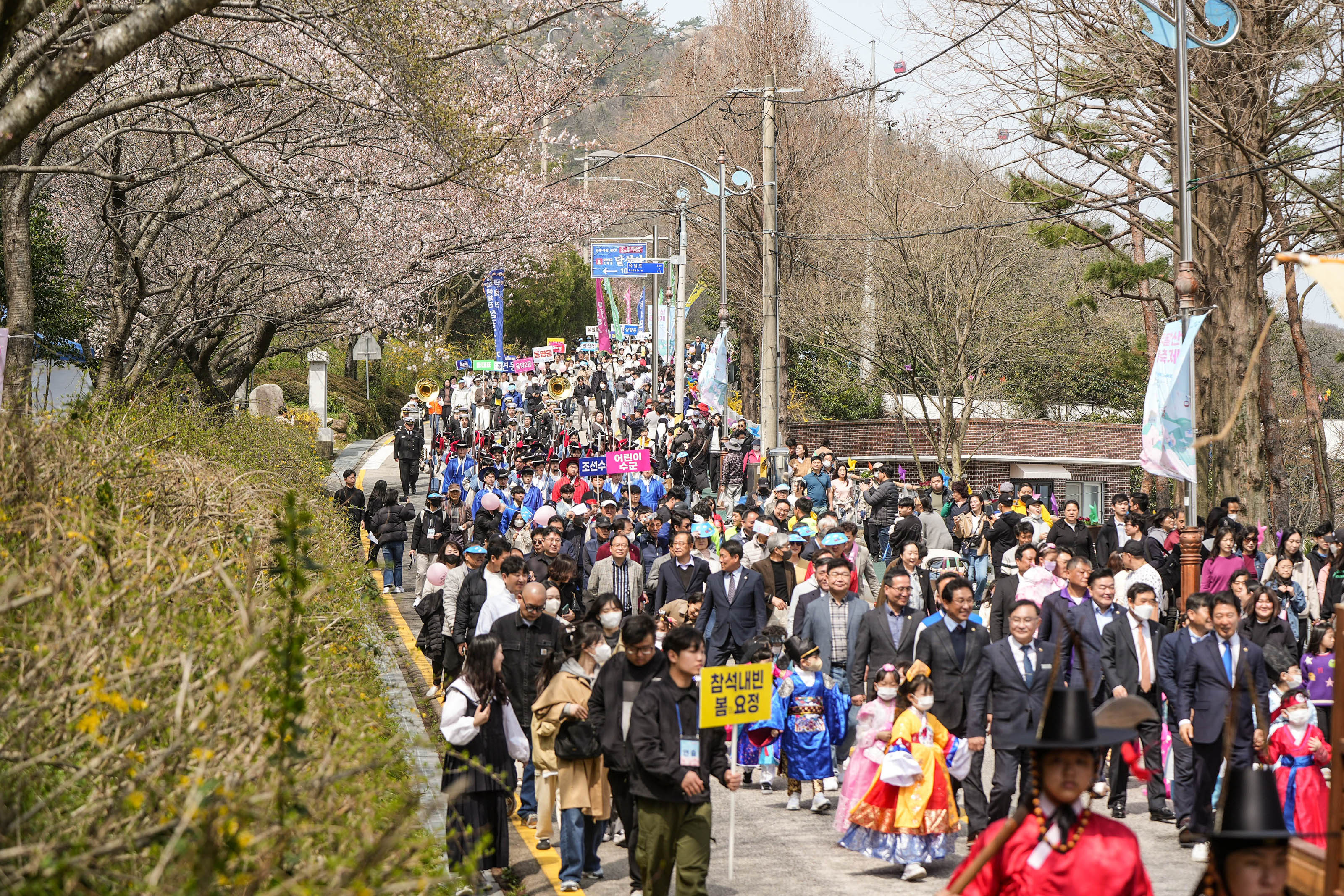 행사라를 참여한 사람들과 참석내빈들이 한복을 입은 어린 아이들의 손을 잡고 걷는 모습의 사진