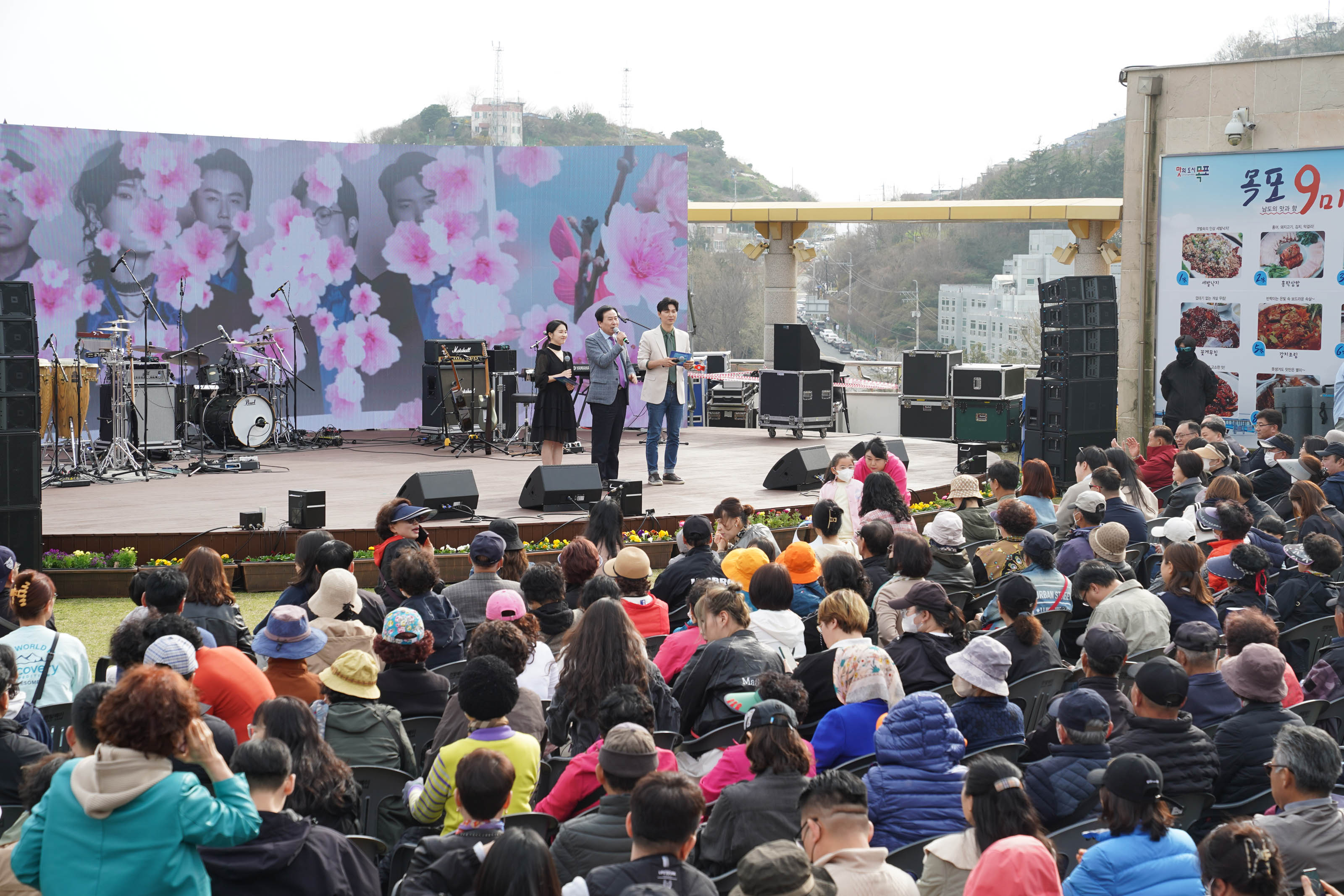 토크콘서트 무대 위에서 검은색 원피스를 입은 여성 사회자와 청바지에 흰 자켓을 걸친 남성 사회자 가운데 박홍률 시장이 마이크를 들고 이야기를 전하고 있다.