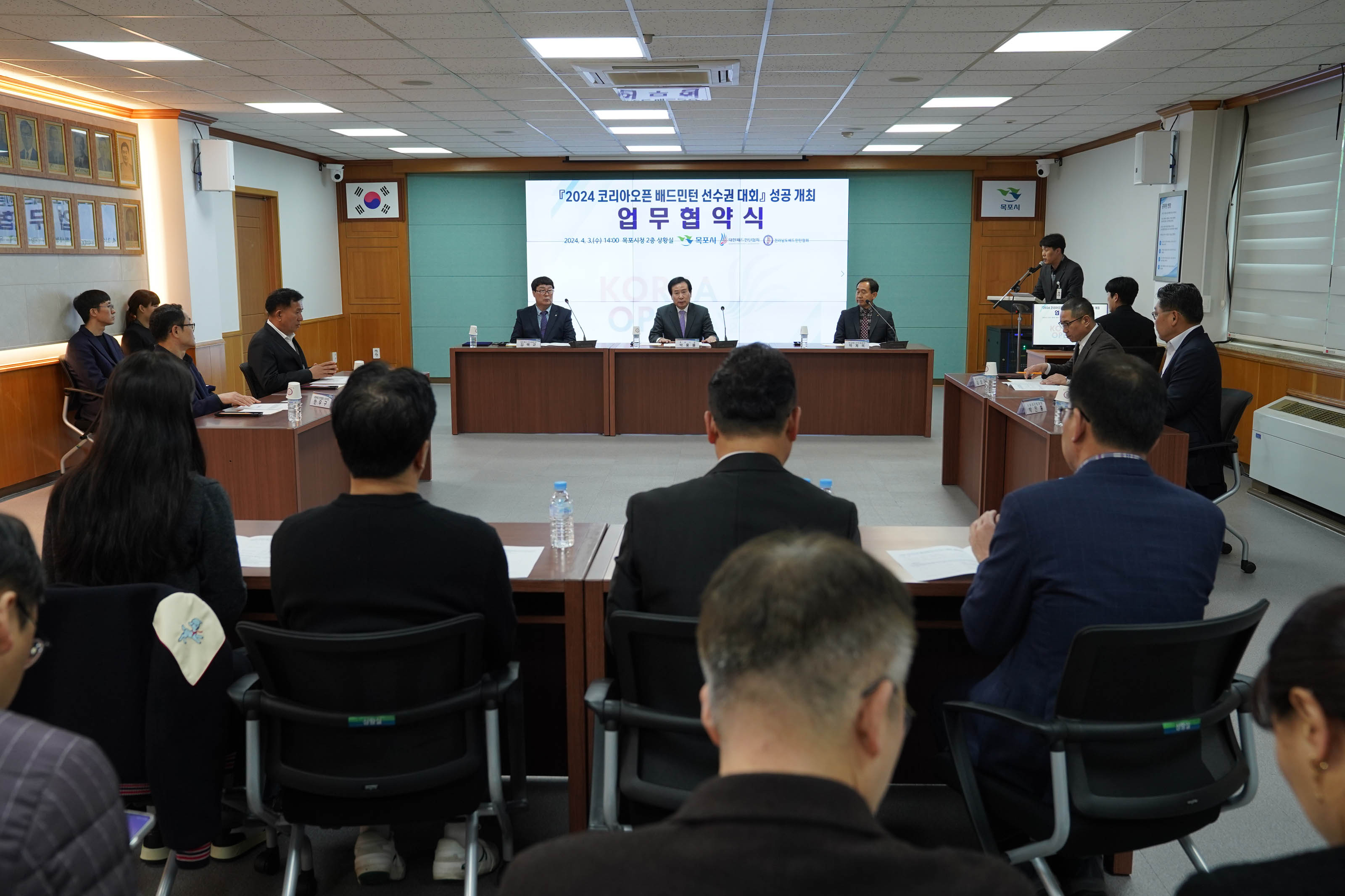 2024 코리아오픈 배드민턴 선수권 대회 성공 개최 업무협약식 플랜카드가 걸려있다. 김택규, 박홍률, 박계옥을 중심으로 협약식이 이루어지고 있다.