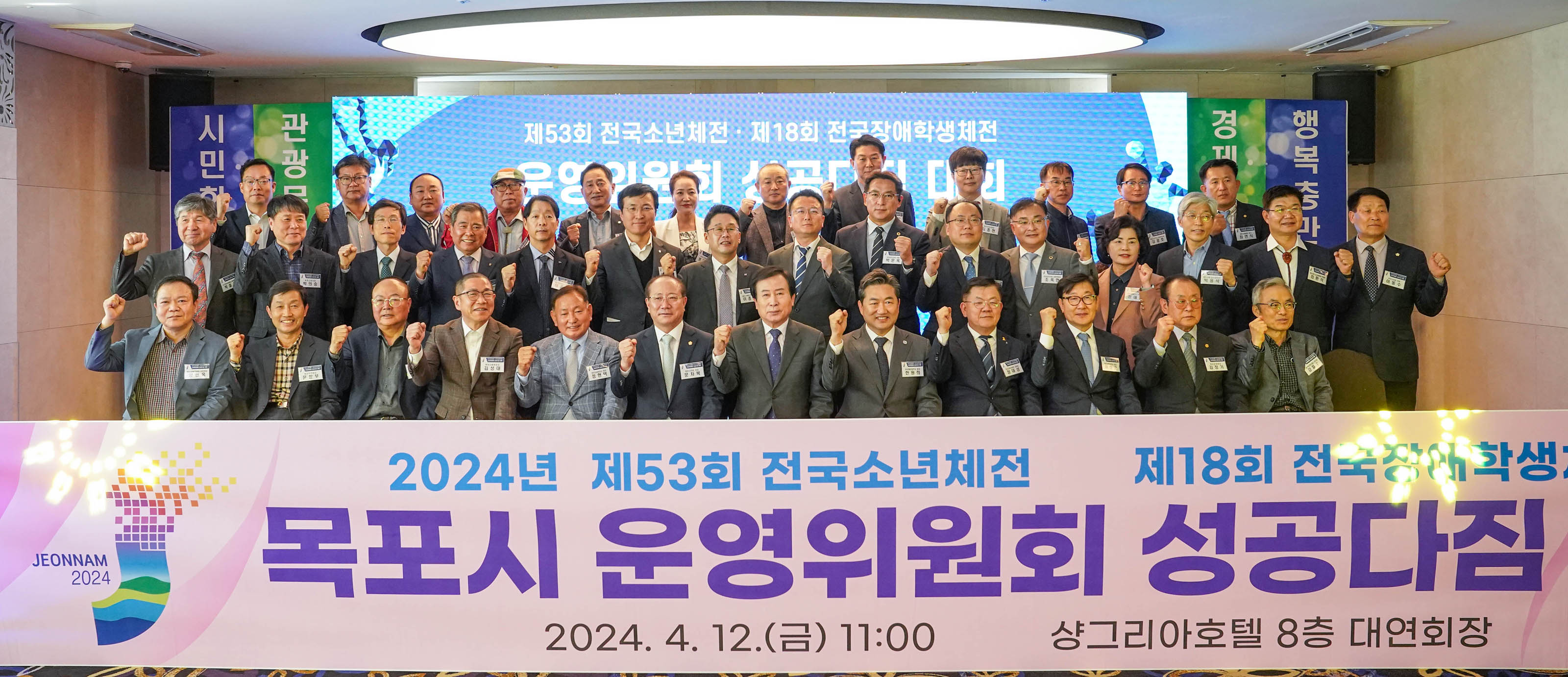 2024녀 제53회 전국소년체전 제18회 전국장애학생체전 목포시 운영위원회 성공다짐 대회 2024.4.12(금)11:00 샹그리아호텔 8층 대연회장 현수막을 앞에두고 참석자들과 함께 화이팅포즈를 취하고있는 박홍률 시장