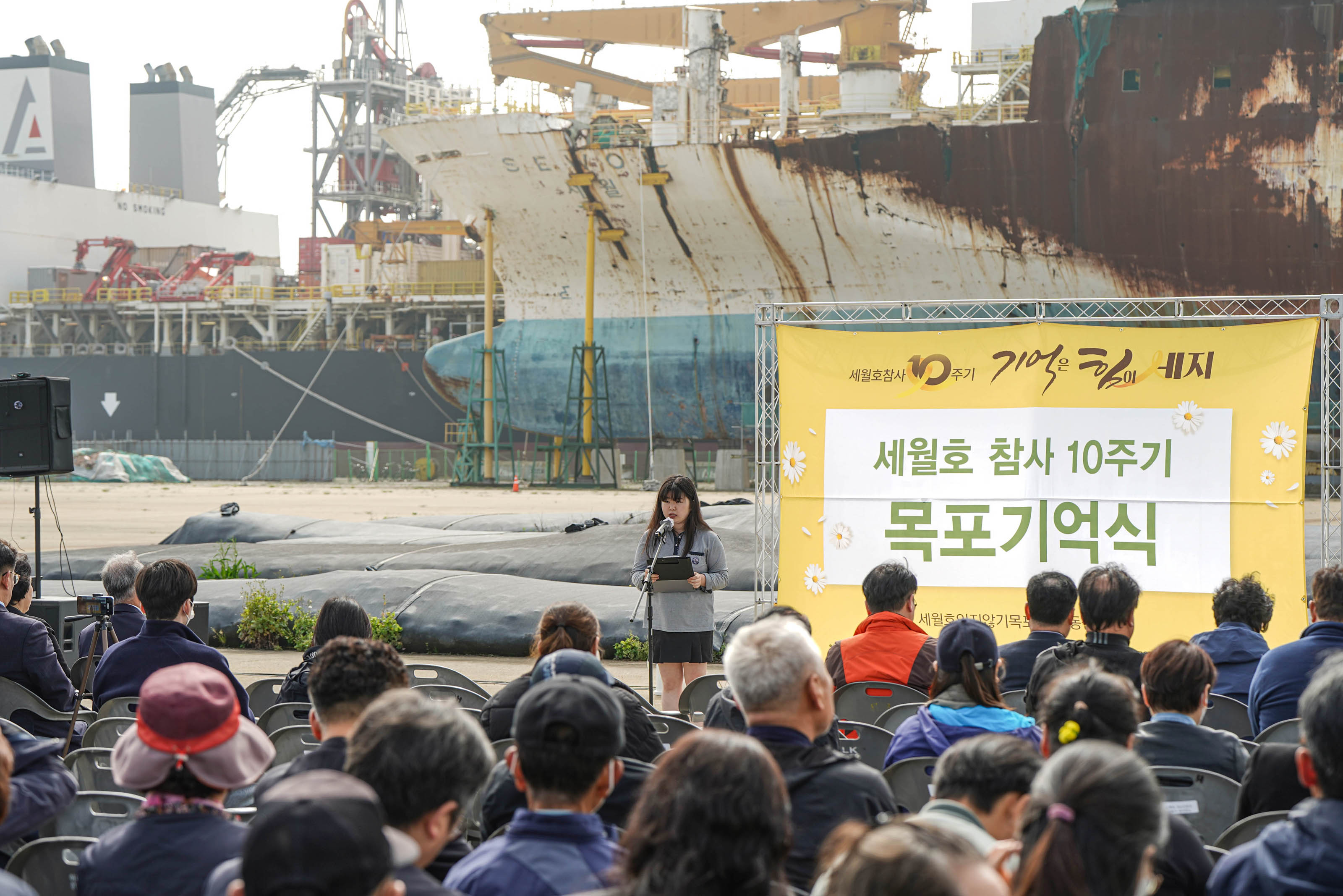 세월호 참사10주기 기억은 힘이 세지 세월호 참사 10주기 목포기억식 현수막을 배경으로 발표하고있는 여학생 발표자와 앉아서 경청하는 청중들