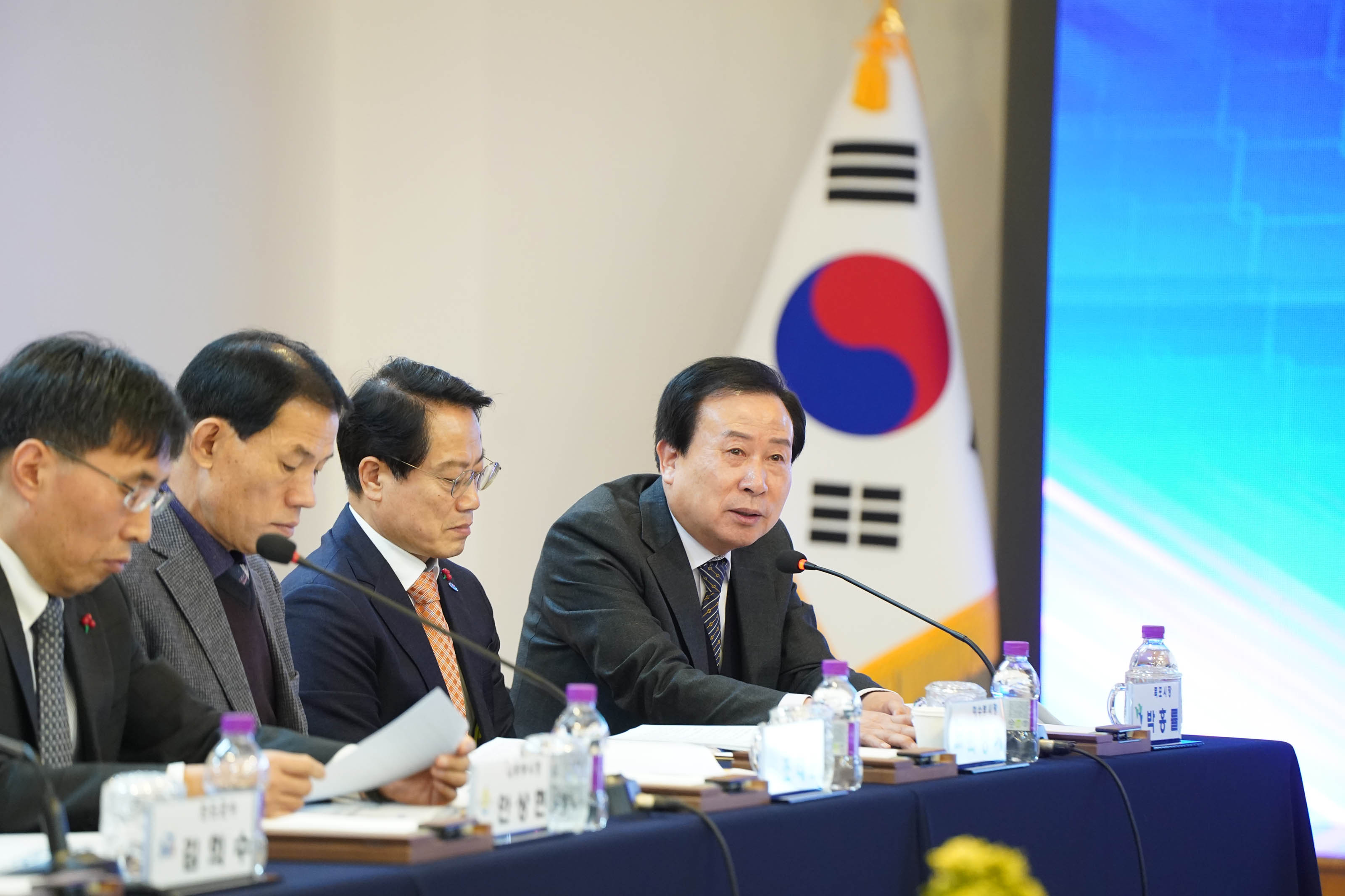 전남시장군수협의회 정례회에서 박홍률 시장이 발언하는 모습. 테이블에는 이름표와 생수병이 놓여 있고, 배경에는 태극기가 세워져 있으며, 주변에는 다른 참석자들도 함께 회의에 집중하고 있다.