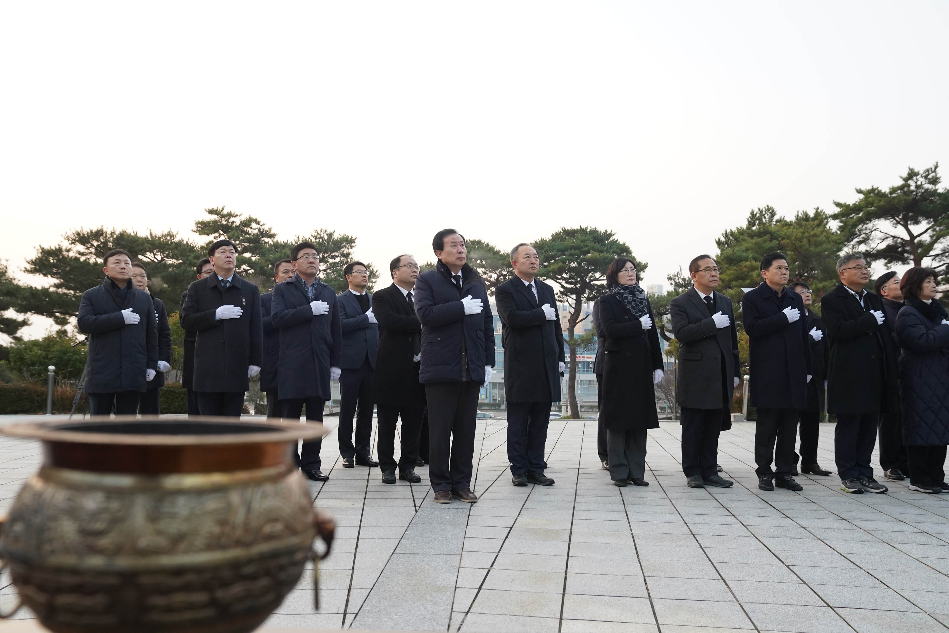 2025년 현충탑 새해맞이 참배 행사에 참석한 20여 명의 인사들이 경의를 표하며 서 있는 모습. 가운데 박홍률 목포시장이 포함되어 있으며, 참석자들은 흰 장갑을 착용하고 있다.