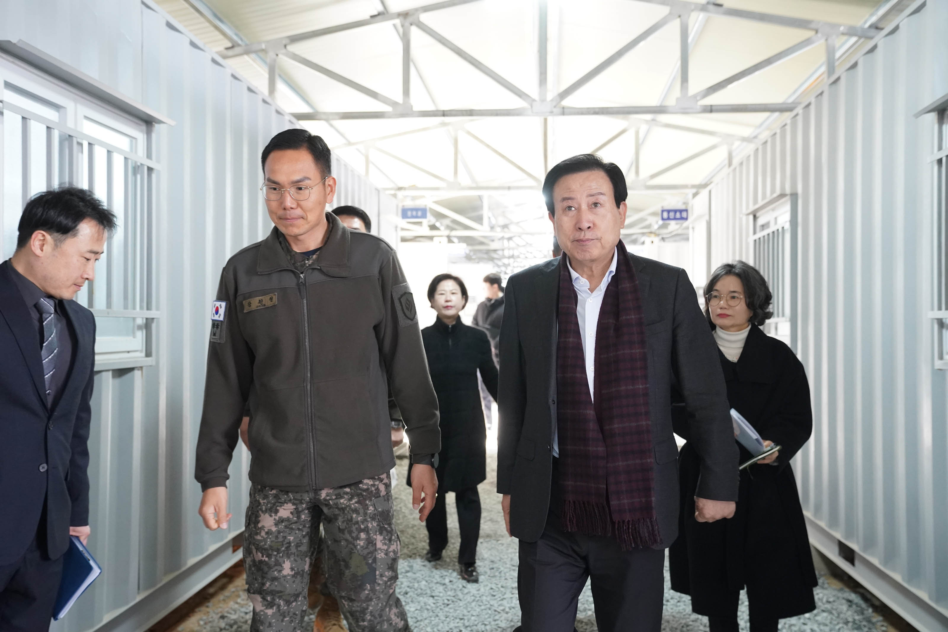 박홍률 목포시장이 군대 부대를 방문하여 군인과 공무원들과 함께 부대 내부를 걷고 있다. 군인은 군복을 입고 있으며, 시장과 동행한 4명의 관계자들도 뒤따르고 있다.
